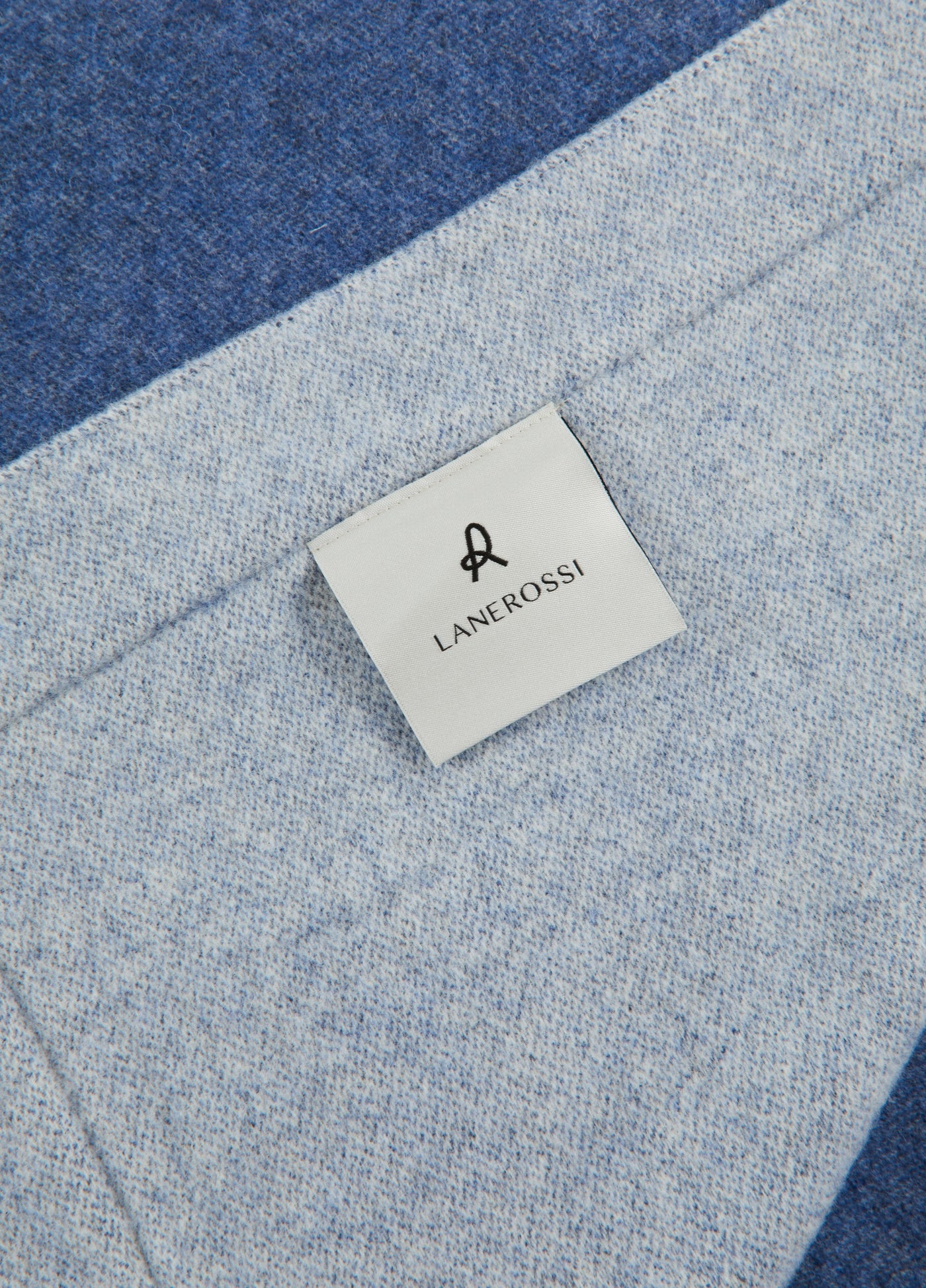 Close-up of Lanerossi woven label on two-tone blue wool blanket corner.