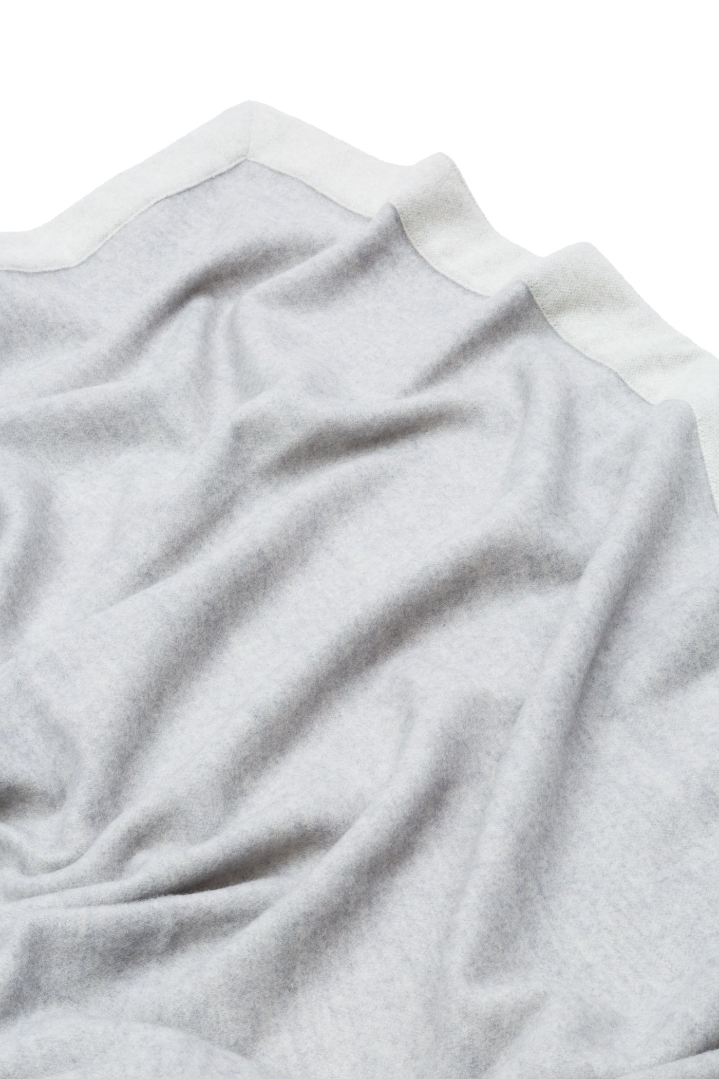 Draped silver-grey blanket with contrast ivory border trim, soft brushed texture visible.