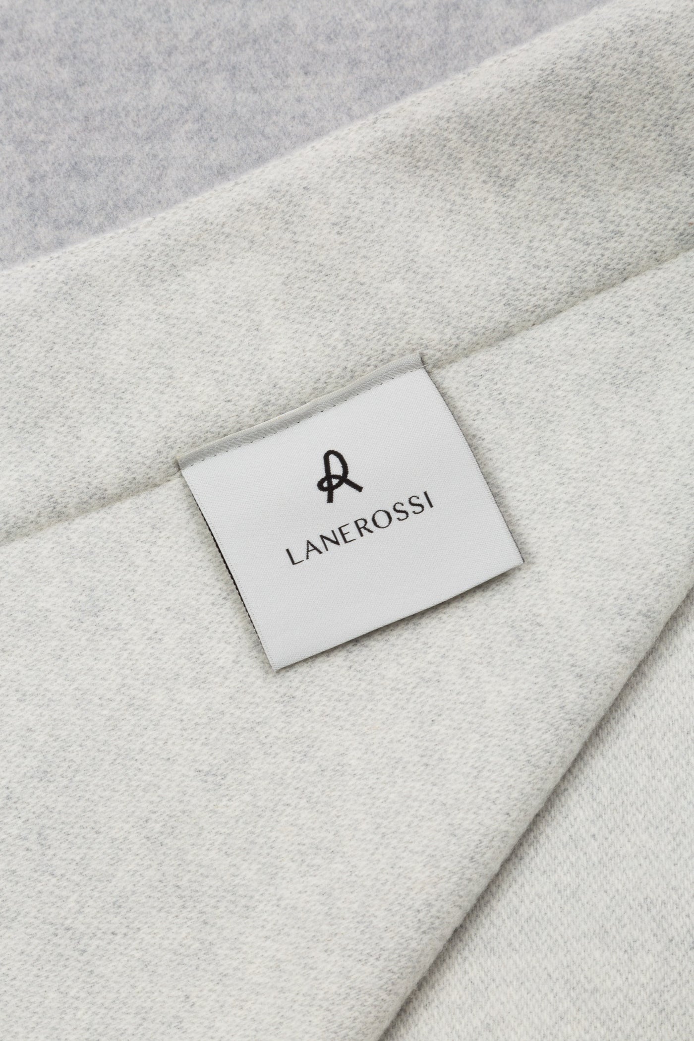 Close-up of Lanerossi woven label on folded ivory wool blanket corner.