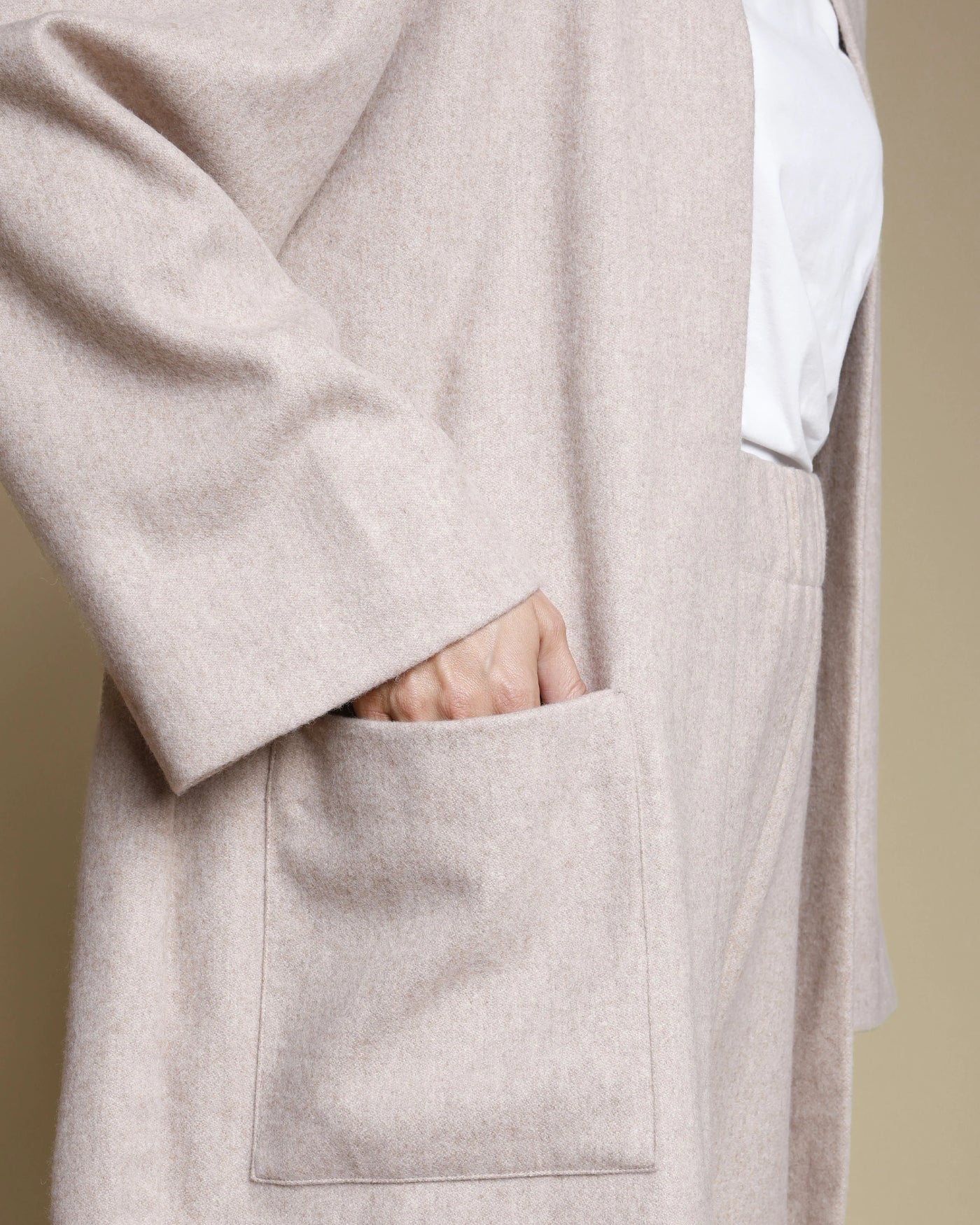 Close-up of oatmeal Lanerossi merino cardigan pocket with hand tucked inside.