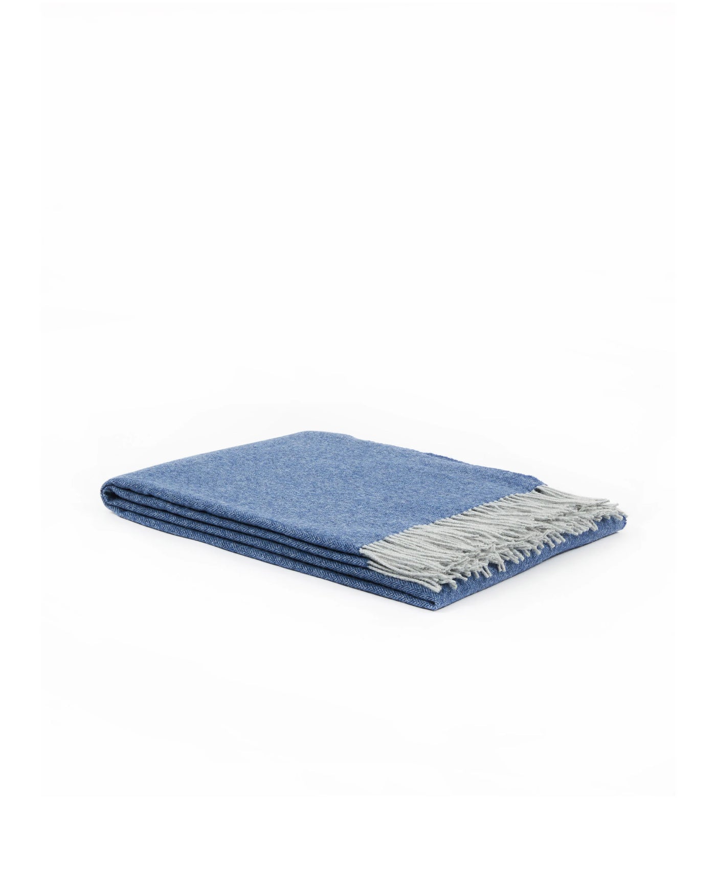 Folded cornflower blue wool throw with contrast silver-grey fringe, angled view.