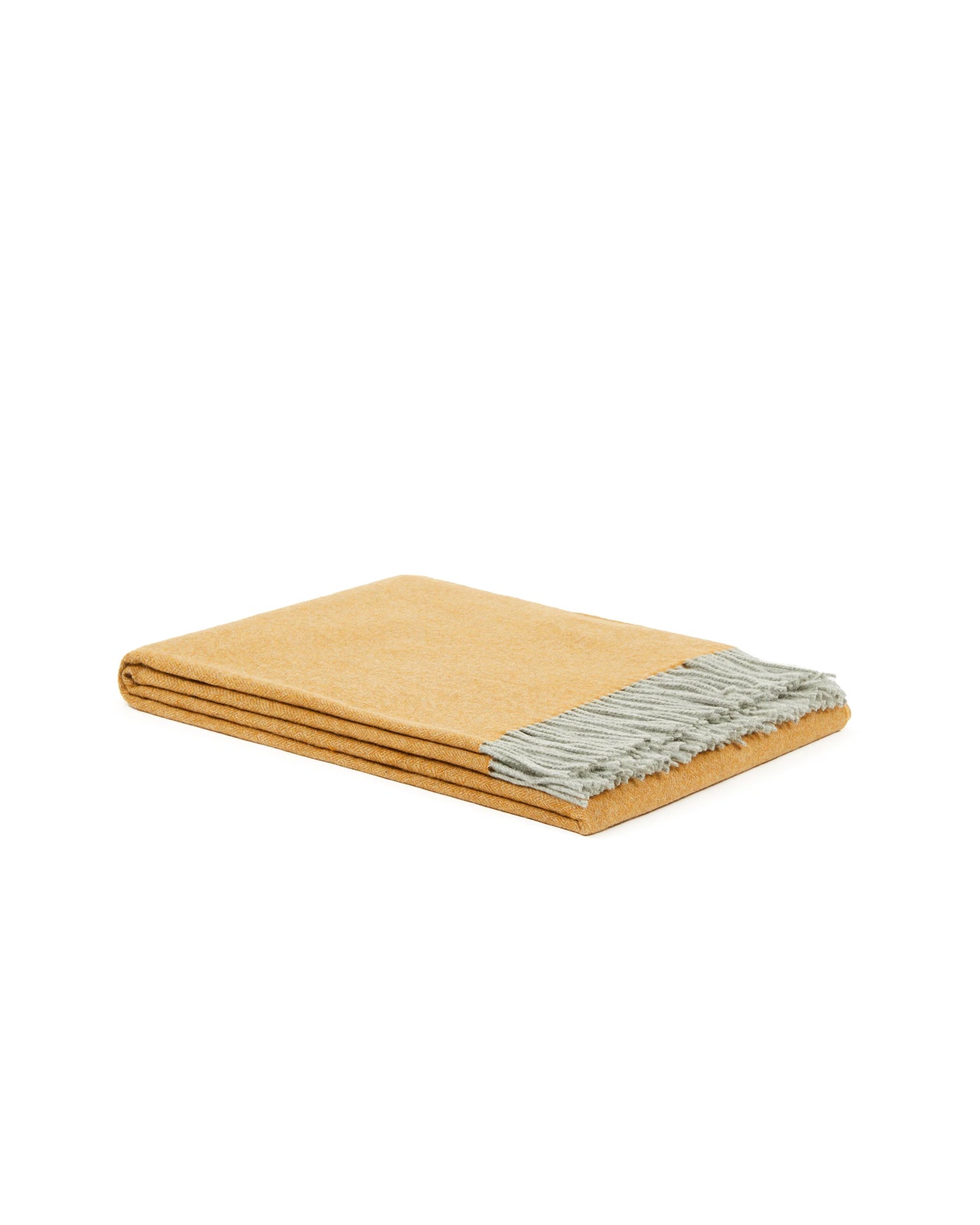 Folded saffron throw with sage fringe trim, shown against white background.