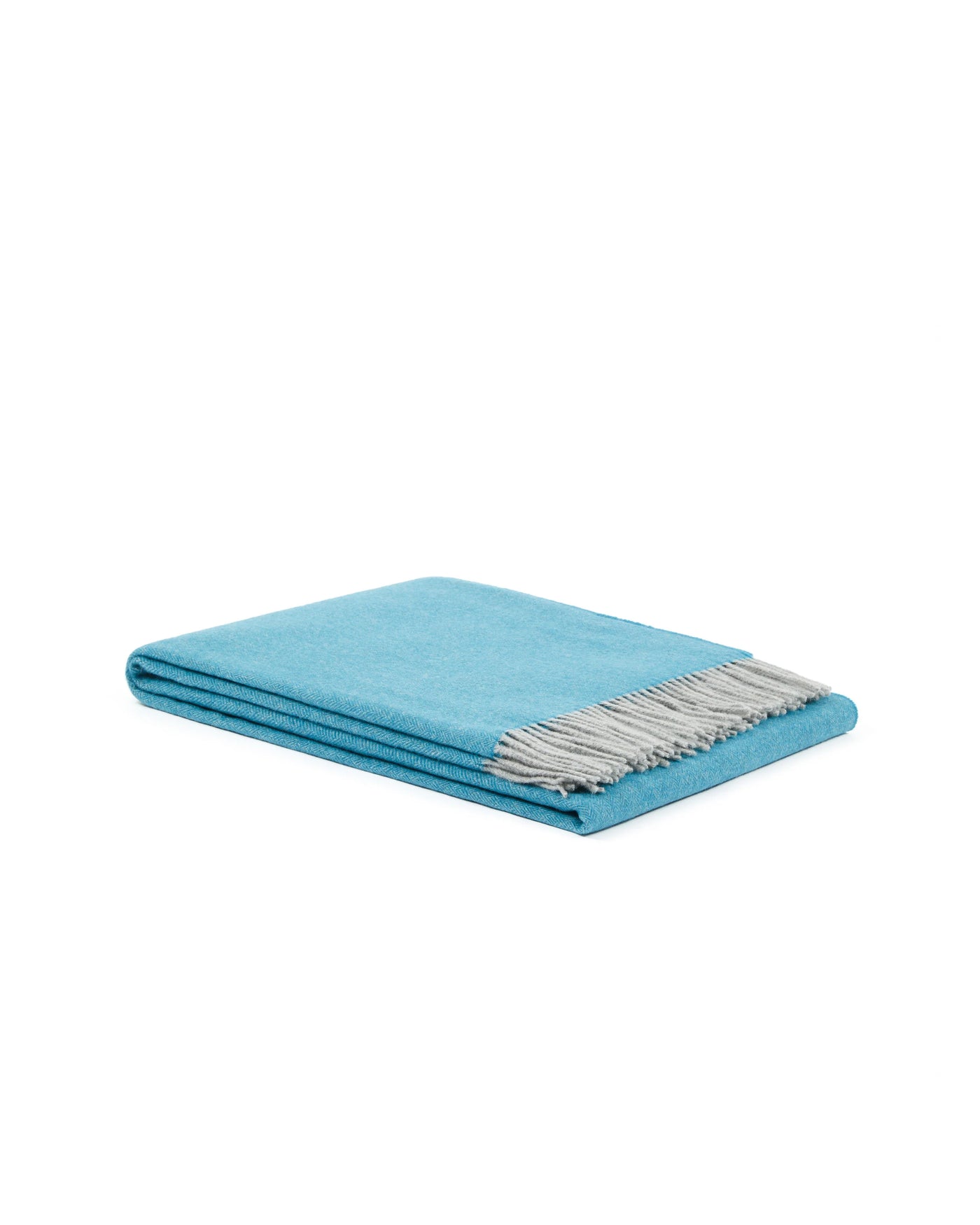 Folded aqua throw with silver-grey fringe, angled view showing layered edges.