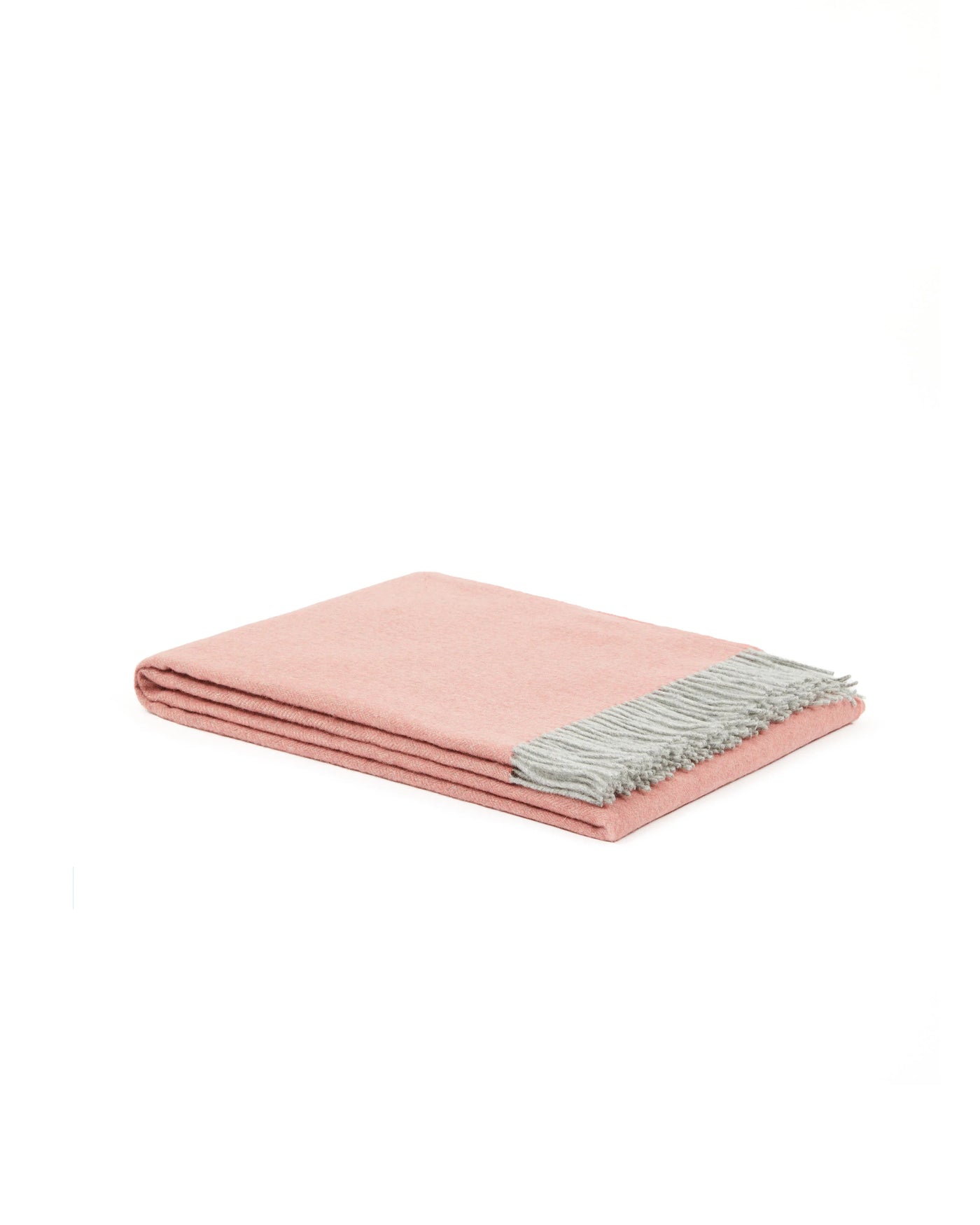 Folded blush throw with contrast silver-grey fringe trim, neatly stacked layers visible.