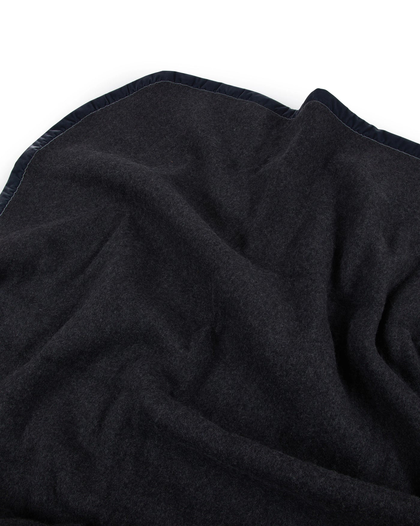 Close-up of Lanerossi Thermo Blanket corner in midnight, showing soft wool drape and contrast trim.