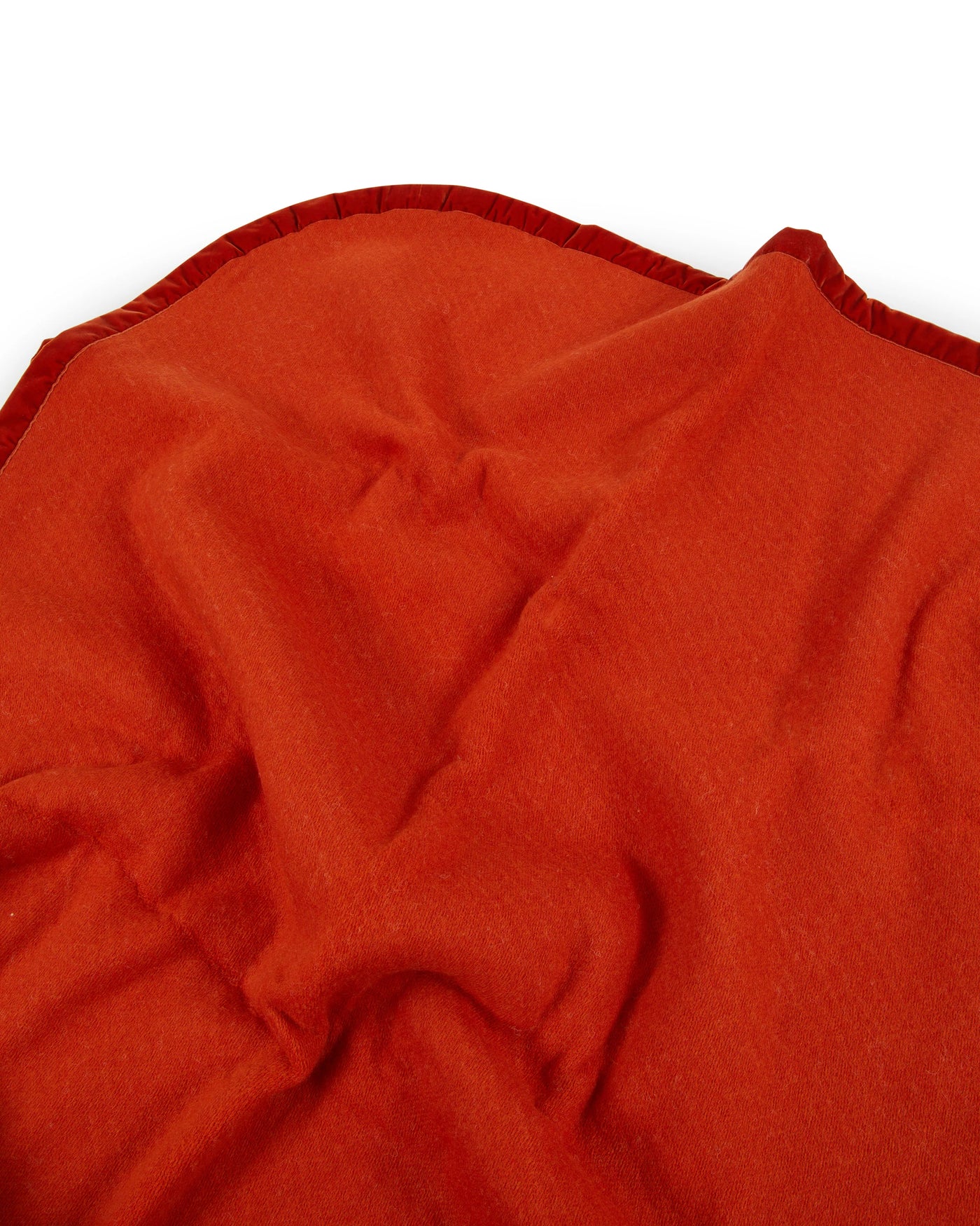 Close-up of Lanerossi Thermo Blanket in rust red, showing folded fabric and contrast trim edge.