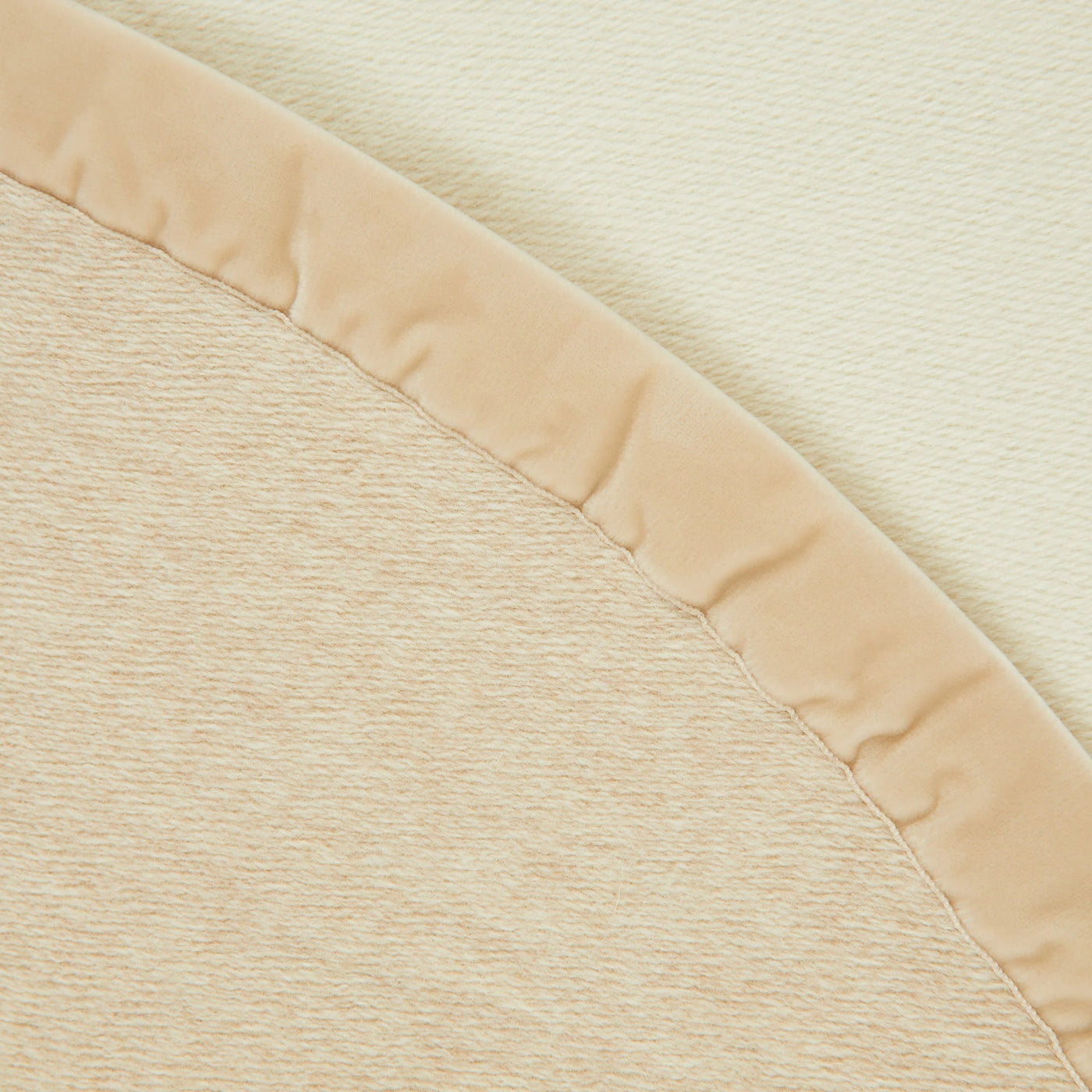 Close-up of Lanerossi Thermo Blanket champagne satin binding edge against ivory textured fleece.