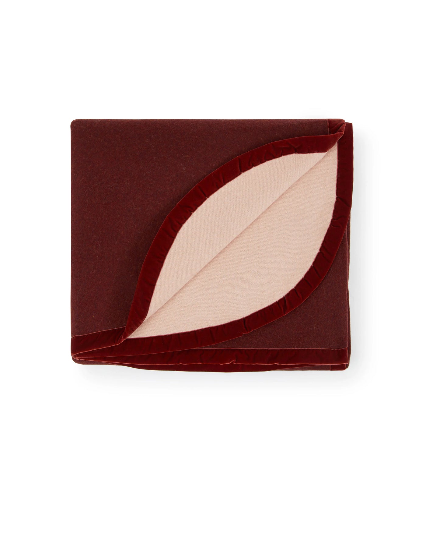 Folded burgundy blanket with blush interior revealed through curved velvet trim opening.