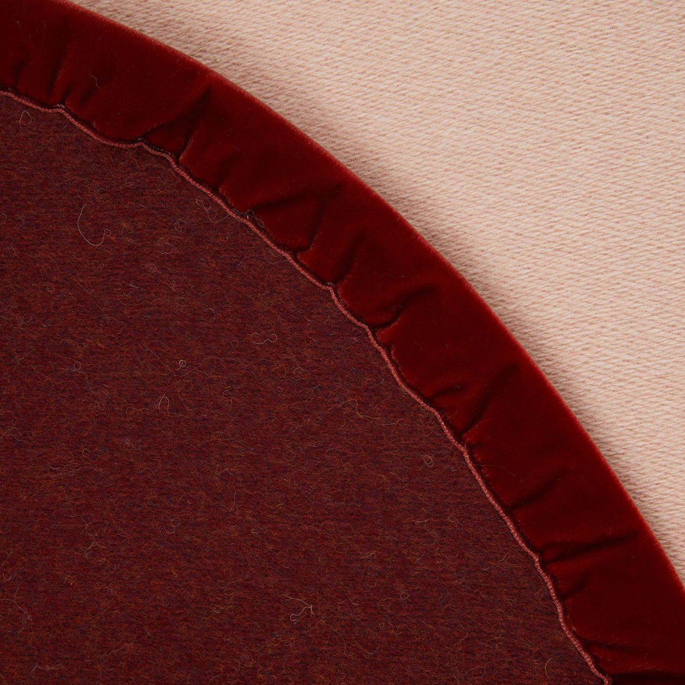 Close-up of Lanerossi Color thermo blanket curved edge with crimson velvet ruffle trim.