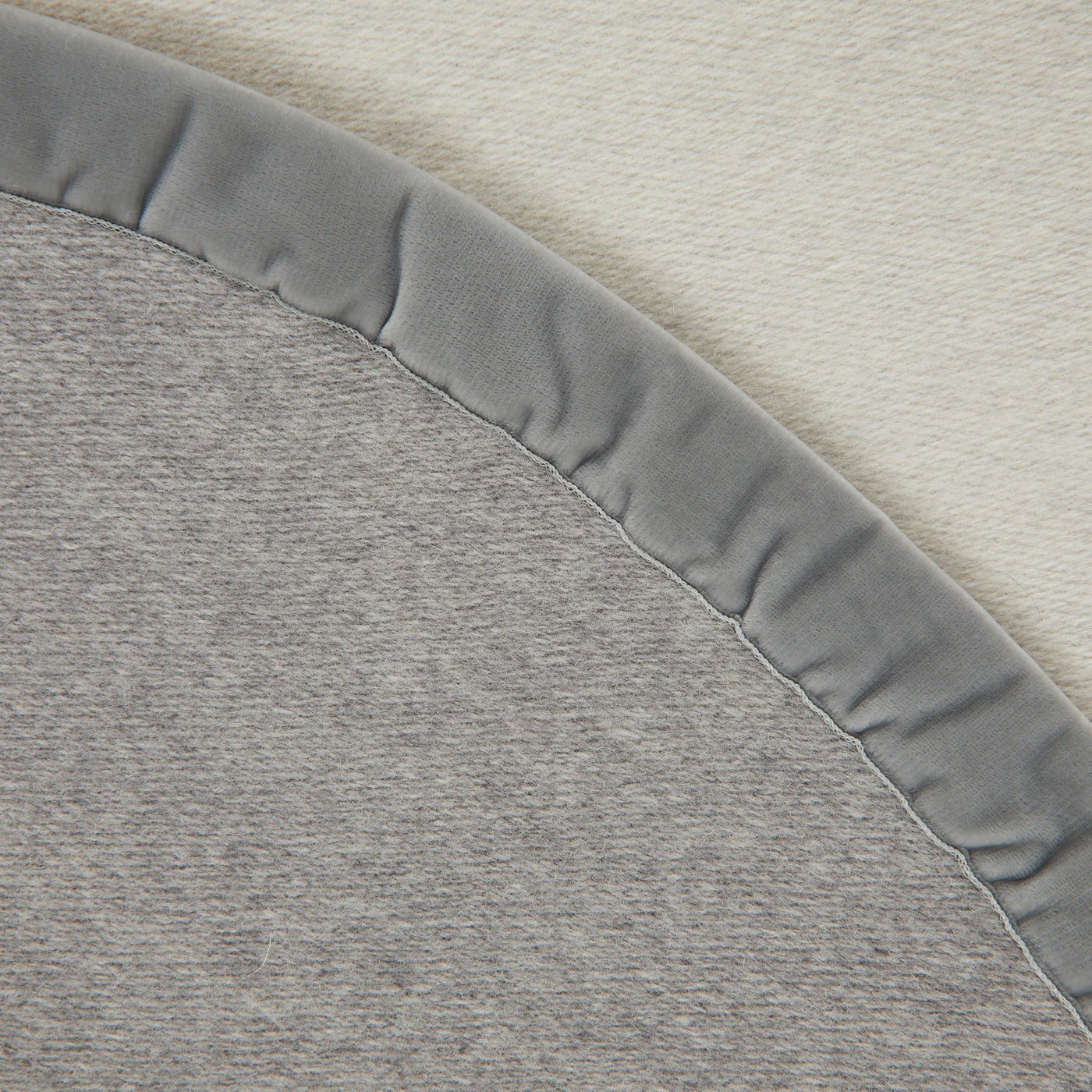 Close-up of Lanerossi Thermo Blanket curved edge, grey knit reverse with ivory face.