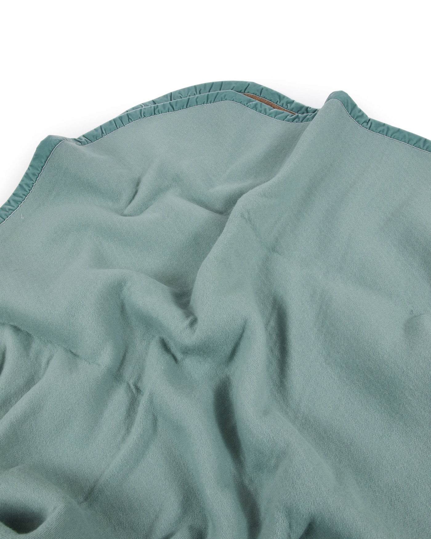 Close-up of Lanerossi thermo blanket in sage green, showing draped fabric and stitched hem detail.