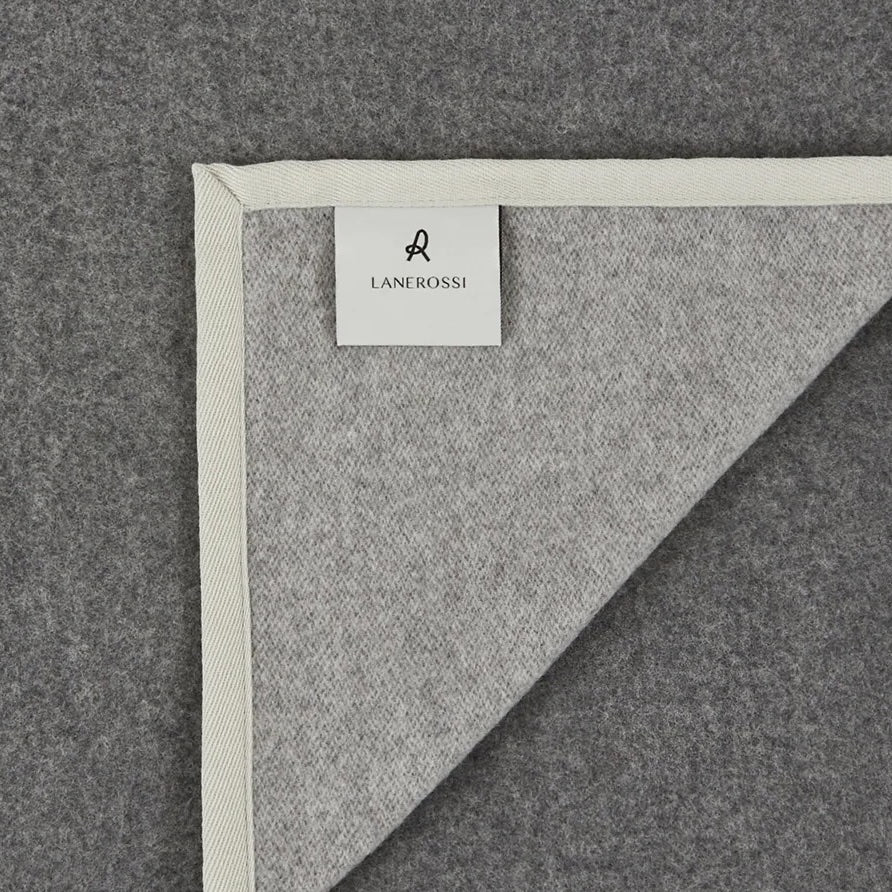 Corner detail of a Lanerossi Cortina blanket in grey wool with ivory herringbone trim binding.