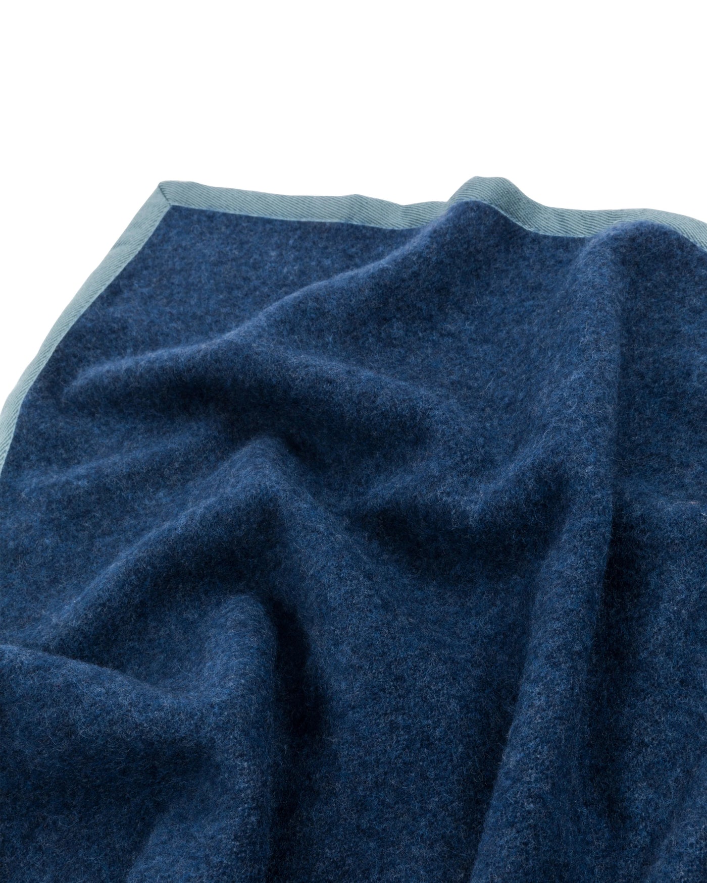 Close-up of navy blue wool blanket with light blue border trim, softly draped.