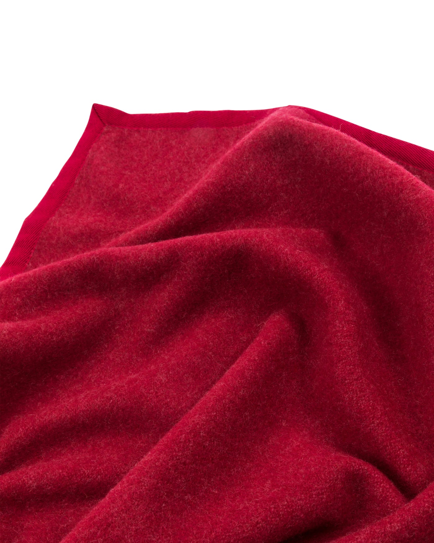 Close-up of crimson wool blanket corner showing soft texture and contrast border trim.