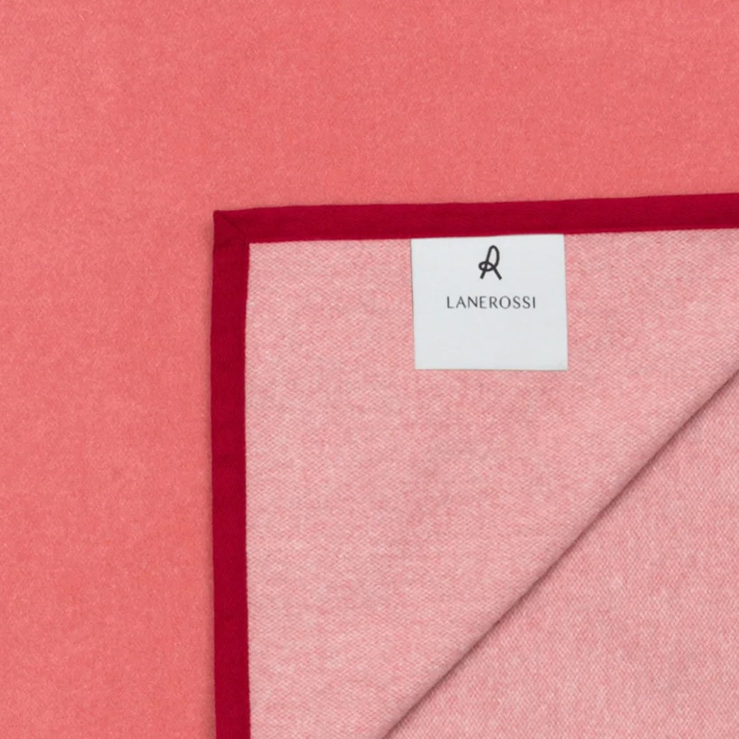 Corner detail of Lanerossi Cortina blanket showing coral herringbone weave and crimson trim edge.