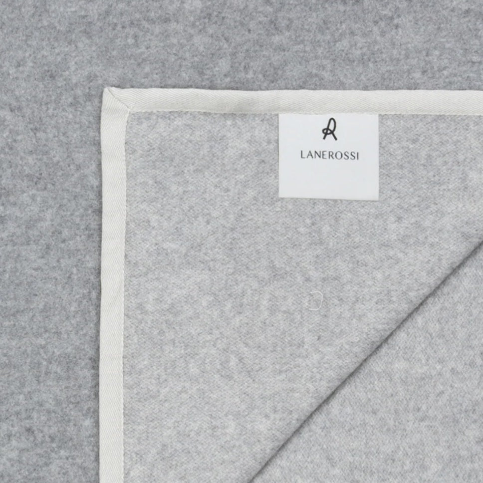 Corner detail of a Lanerossi Cortina blanket in heather grey with ivory blanket-stitch trim.