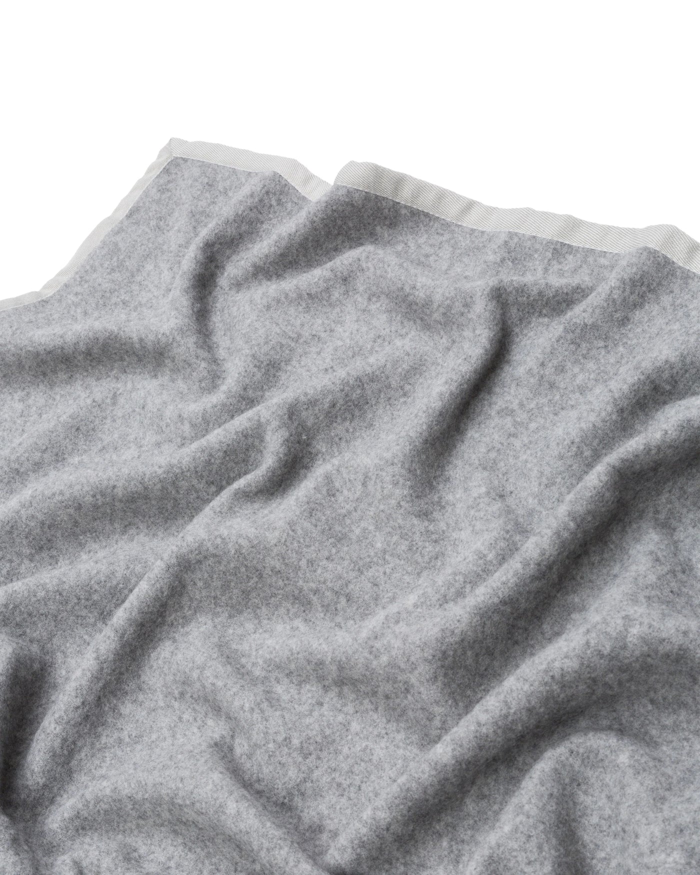 Draped grey wool blanket showing ivory satin trim edge detail.