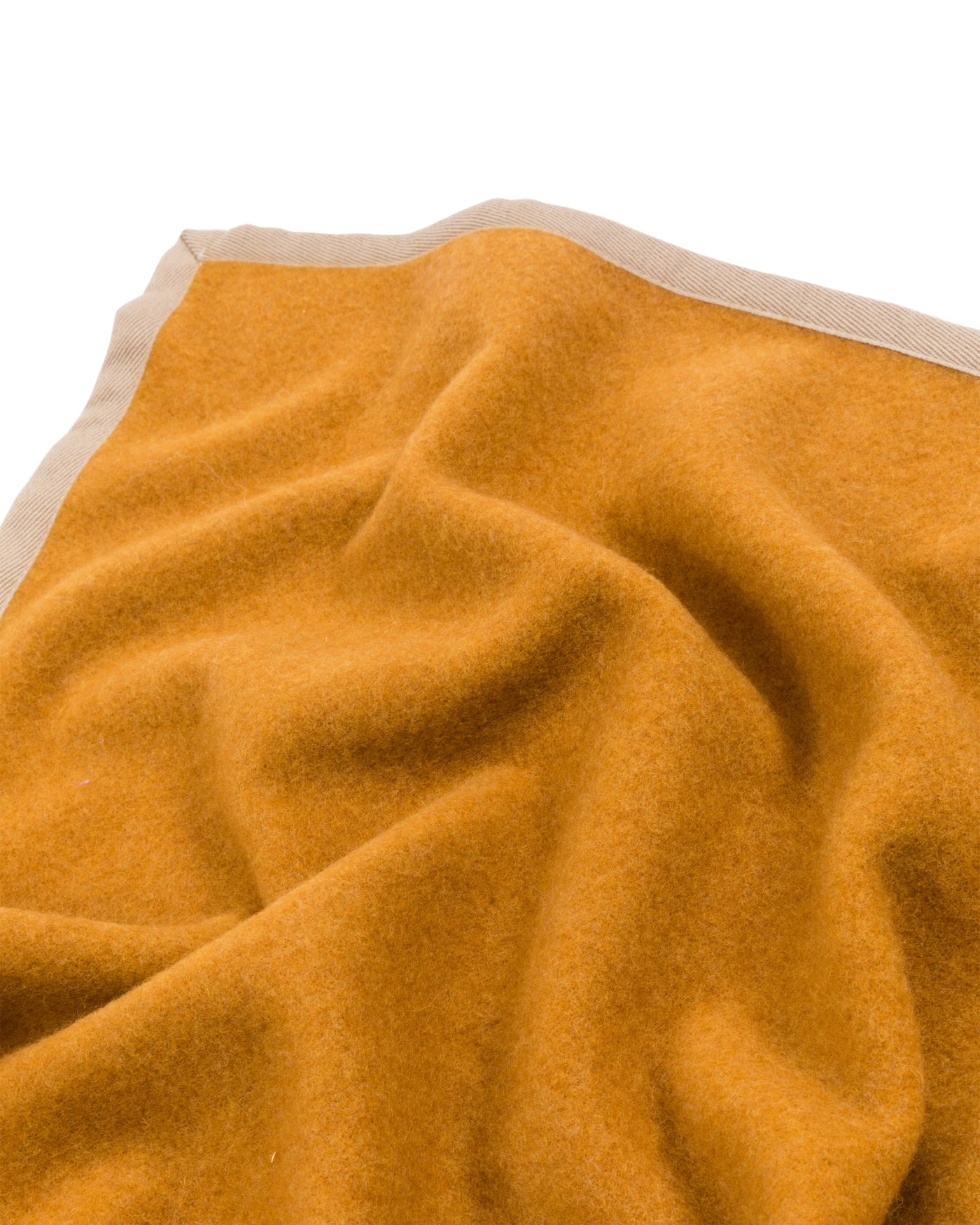 Close-up of saffron wool blanket corner showing sand contrast border trim.