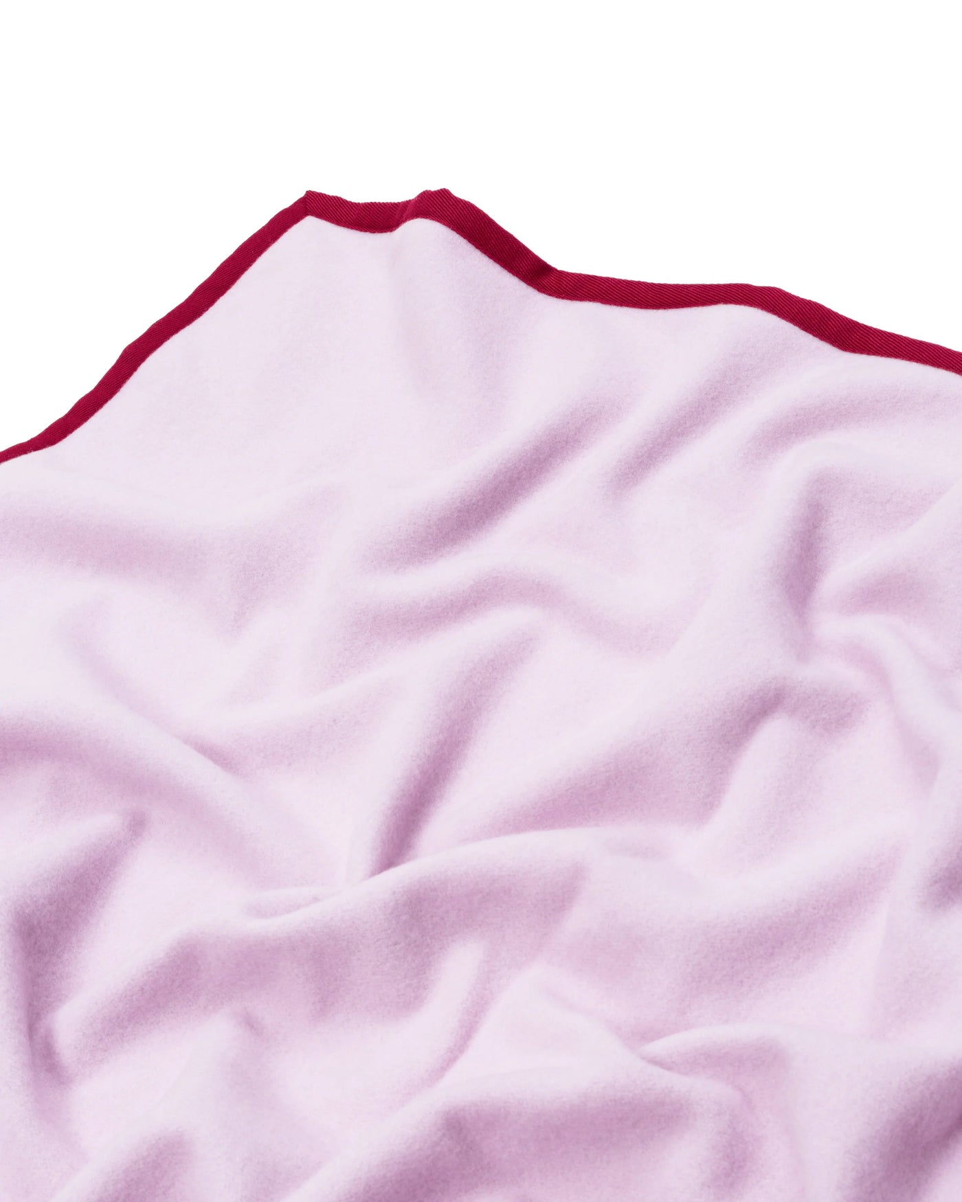 Close-up of blush Lanerossi Cortina blanket corner with crimson contrast trim.