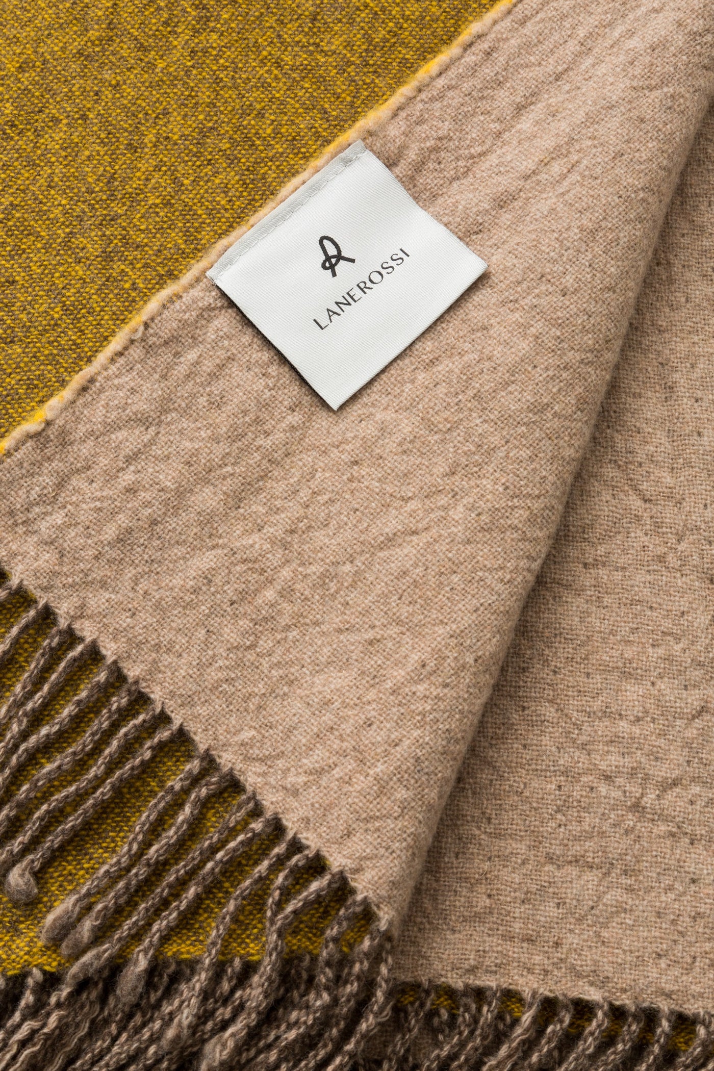 Close-up of Lanerossi Dioniso throw showing mustard and taupe colorblock panels with fringe detail.