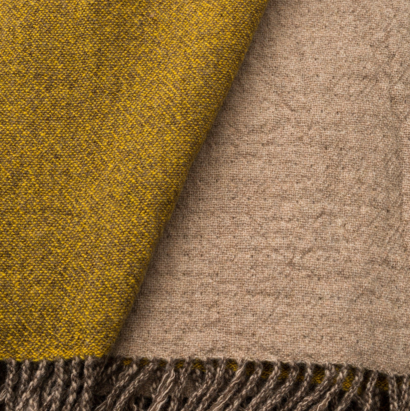 Close-up of Lanerossi Dioniso throw showing mustard and taupe reversible fabric with fringe trim.