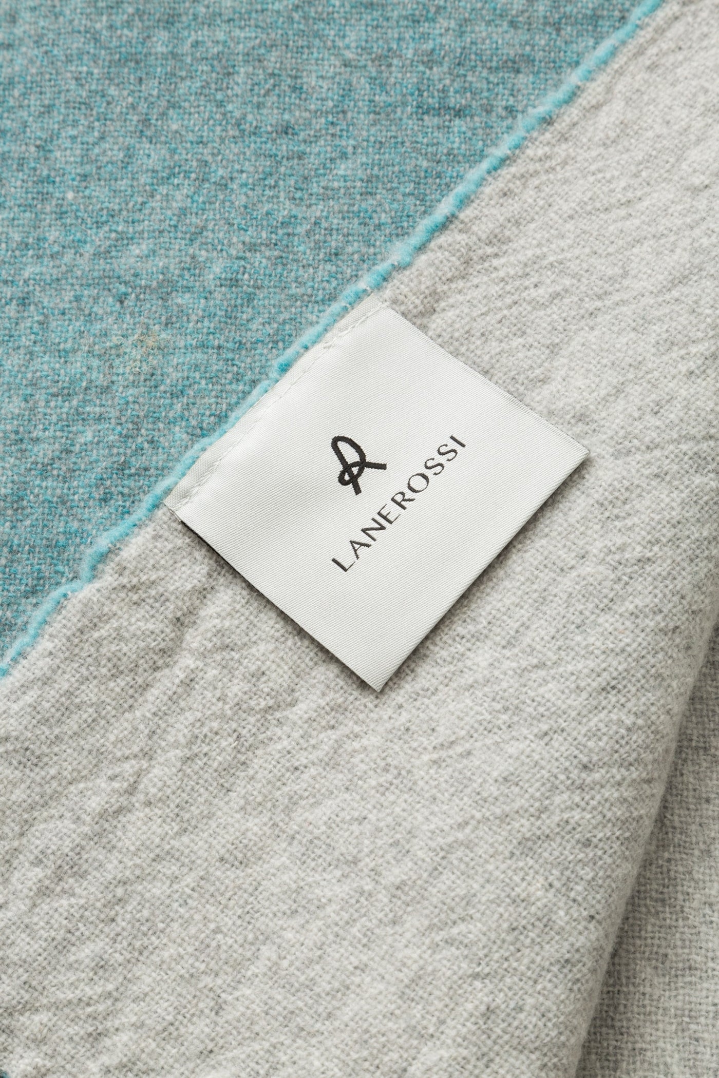 Close-up of Lanerossi Dioniso throw label, teal and dove grey wool visible.
