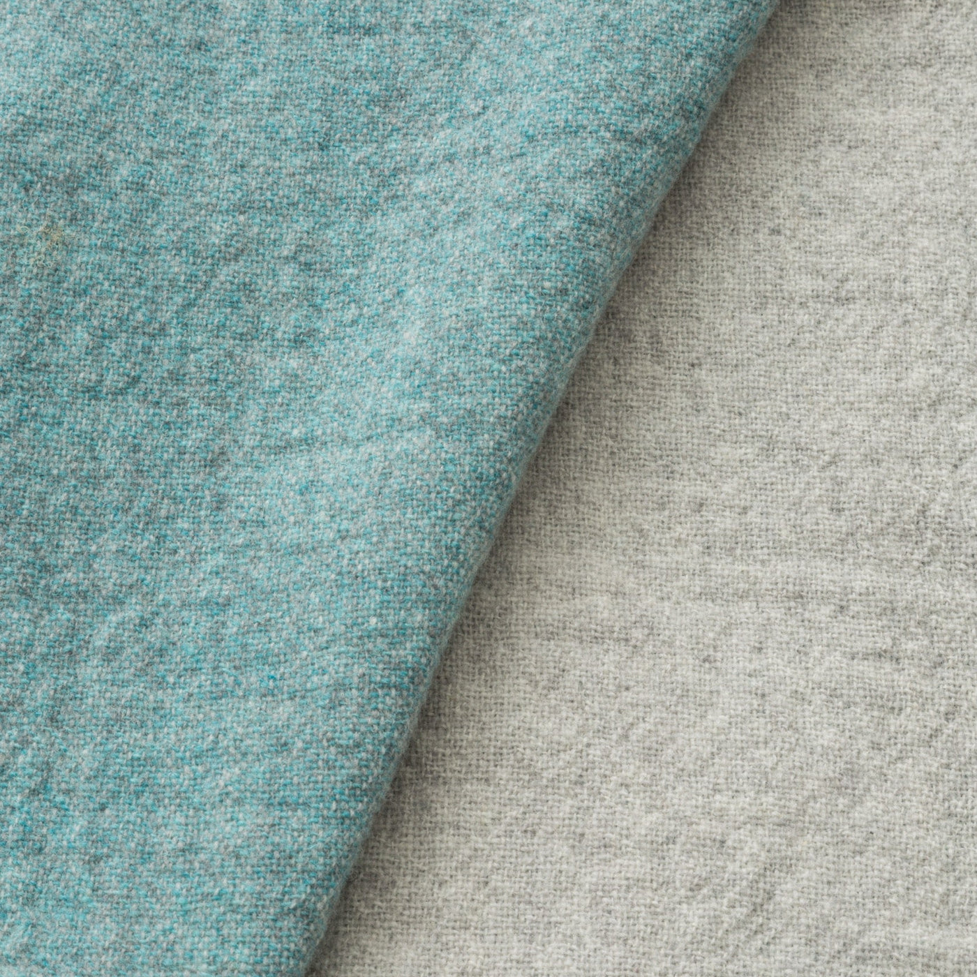 Close-up of Lanerossi Dioniso throw showing aqua and oatmeal reversible wool fabric texture.