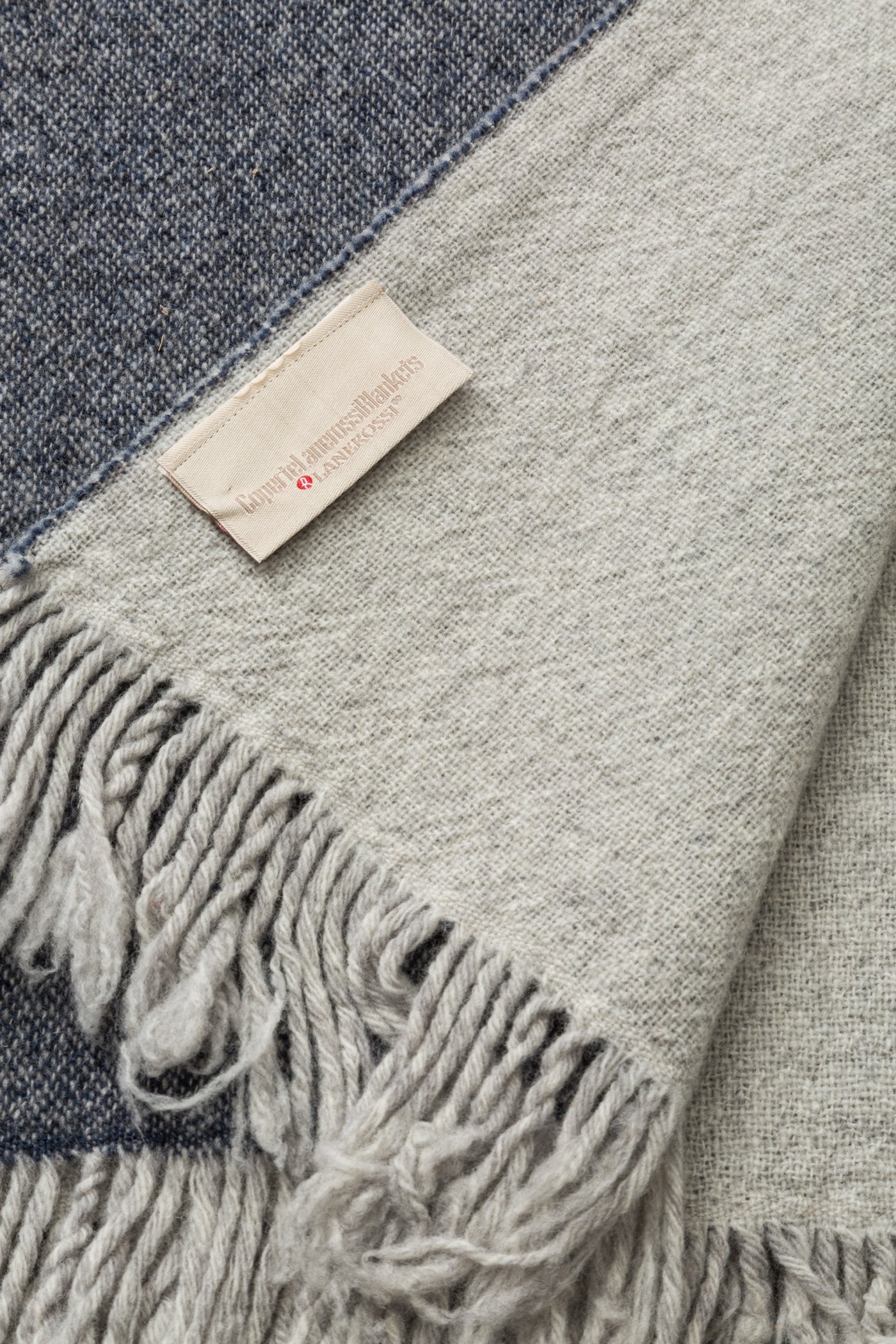 Close-up of Lanerossi Dioniso throw fringe and woven label, silver and navy colorblock detail.