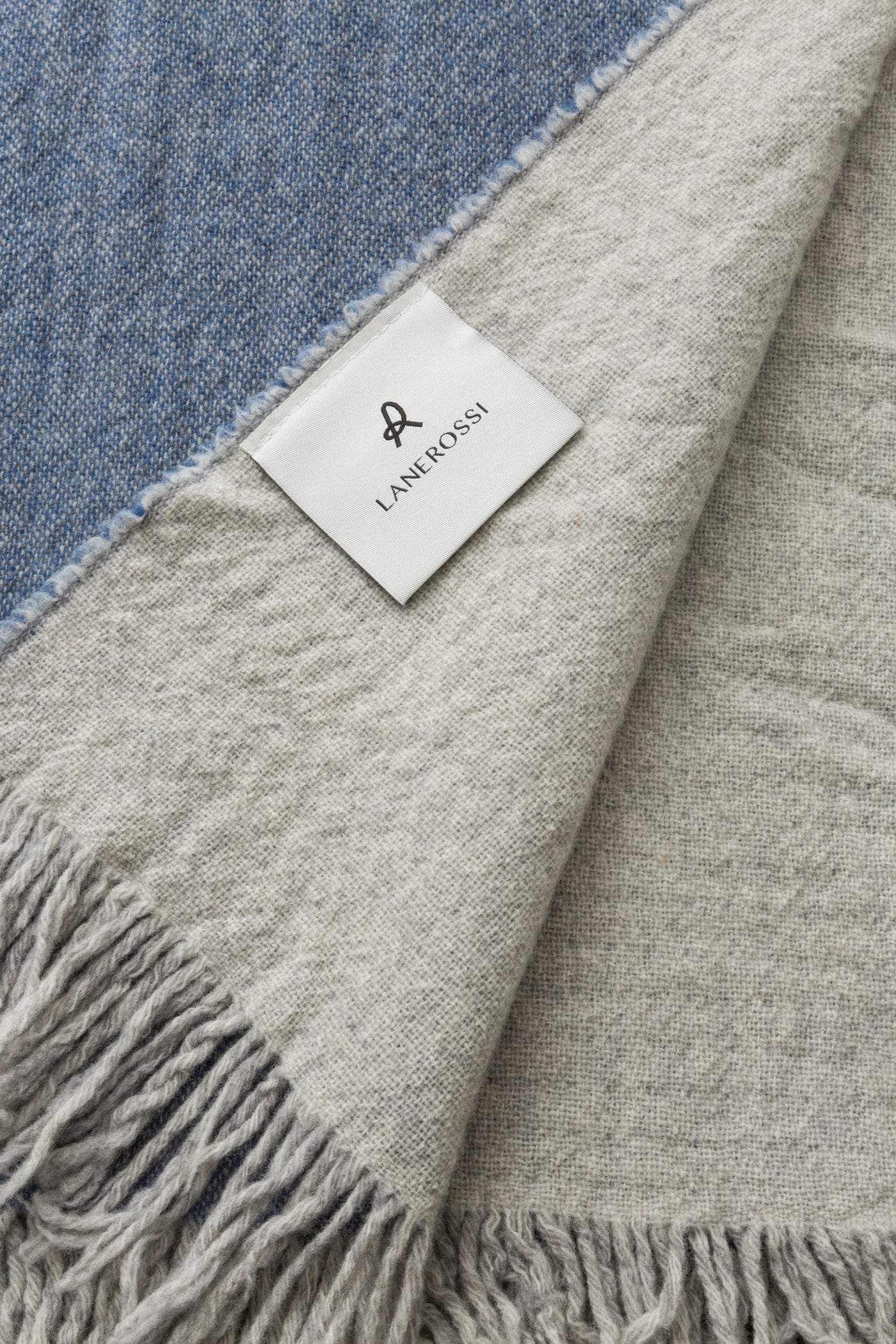Close-up of Lanerossi Dioniso throw corner, showing blue and grey colorblock with fringe trim.