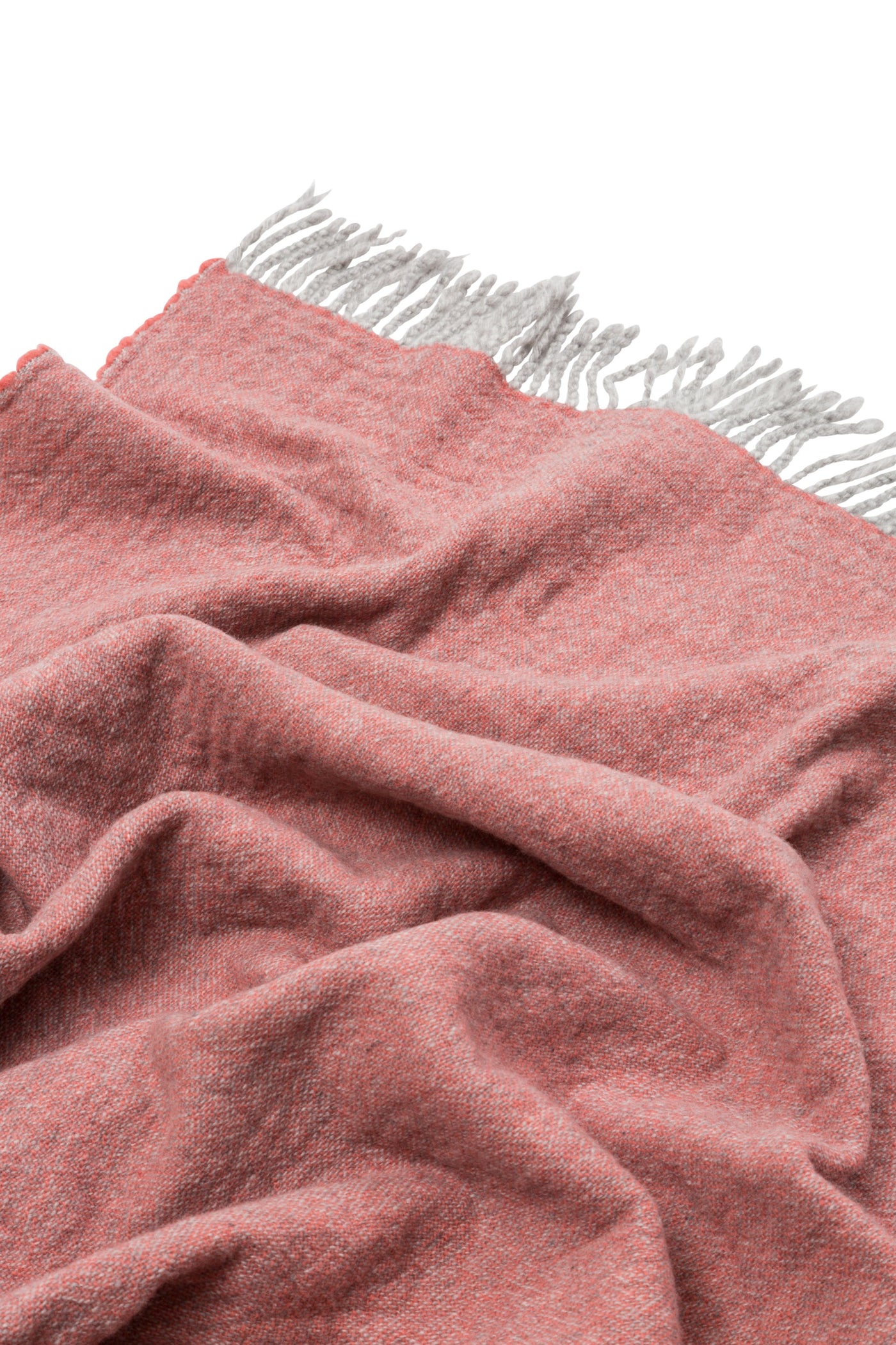 Close-up of draped coral and grey reversible wool throw with fringed edge.
