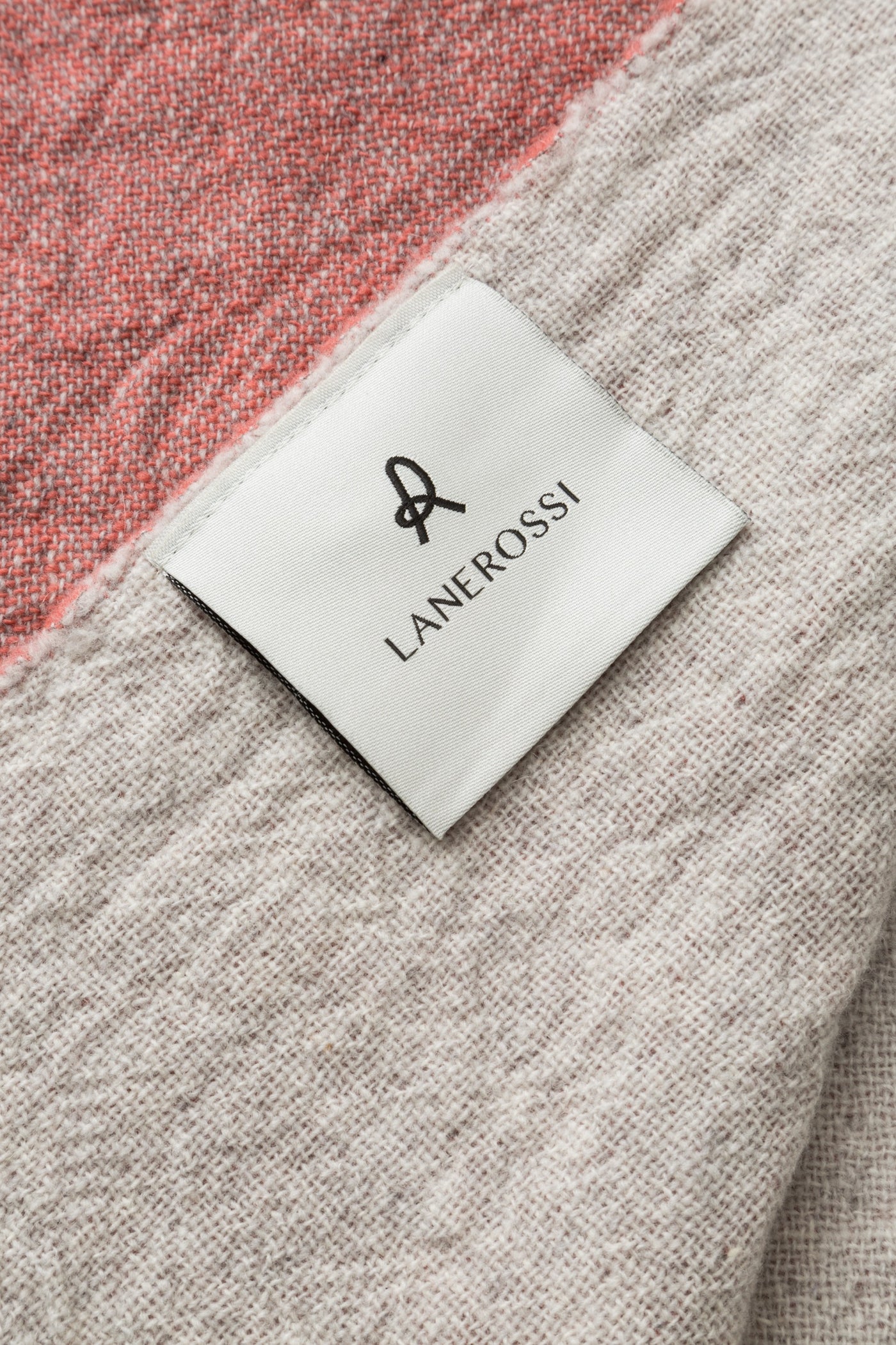 Close-up of Lanerossi Dioniso throw label on ivory and coral wool fabric.