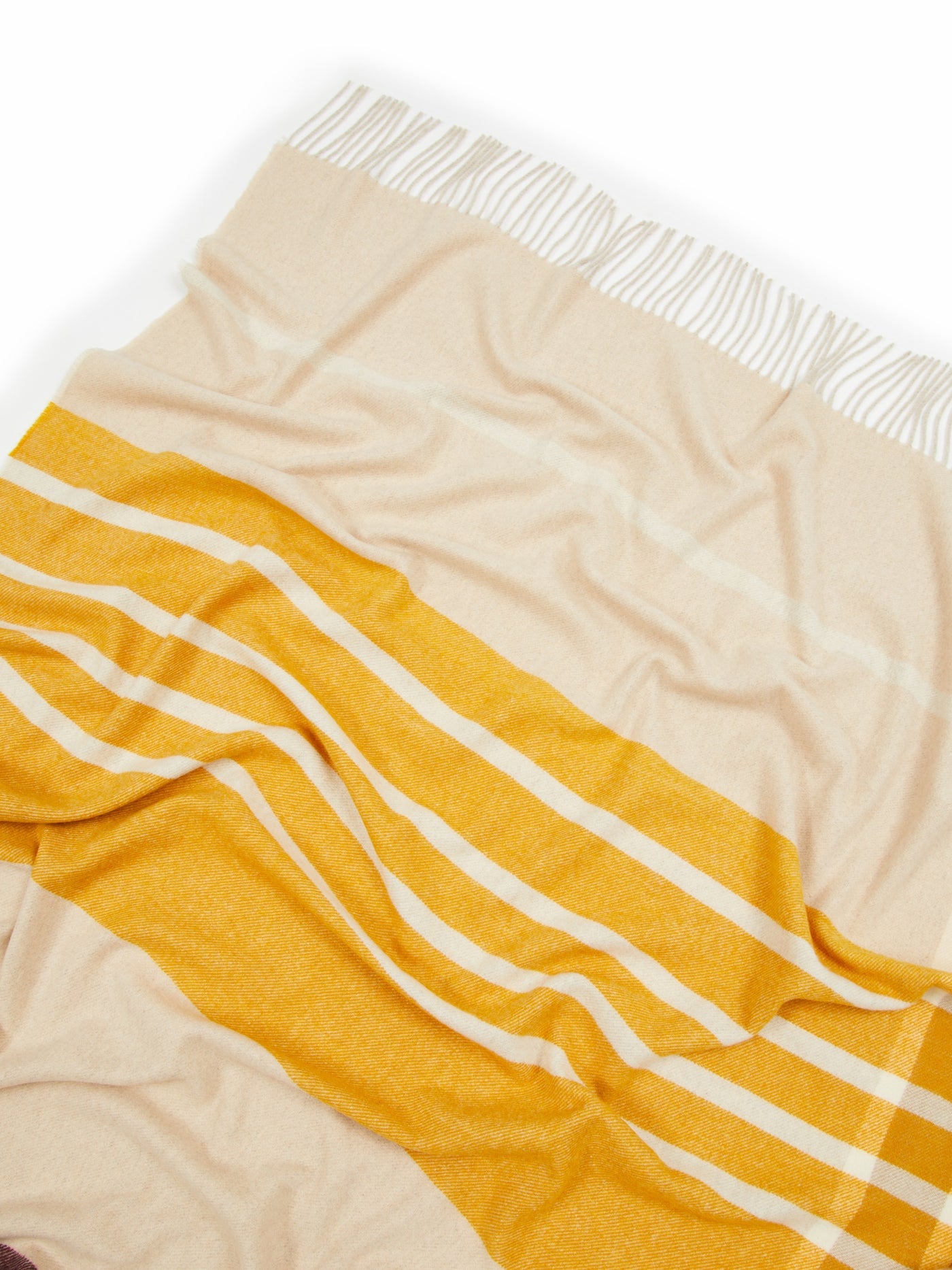 Close-up of marigold and sand stripe pattern with white fringe detail on a woven throw.