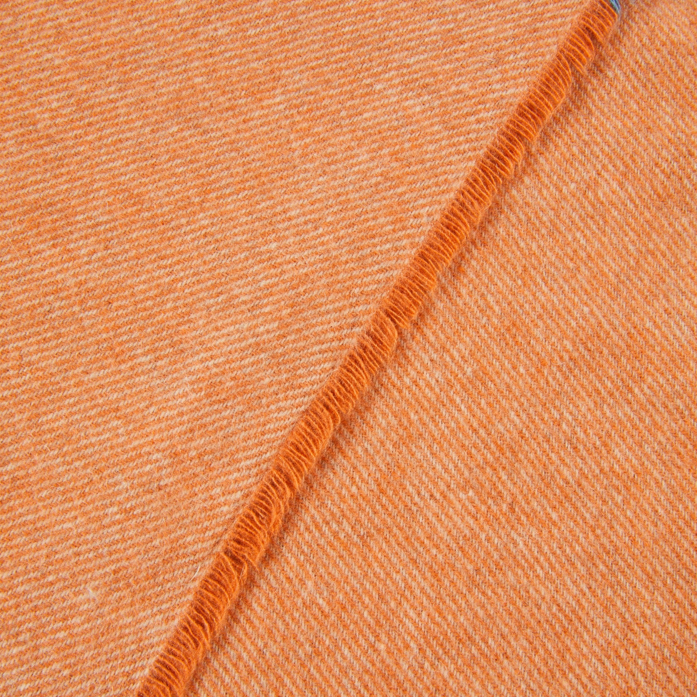 Close-up of tangerine herringbone weave with fringe edge detail.