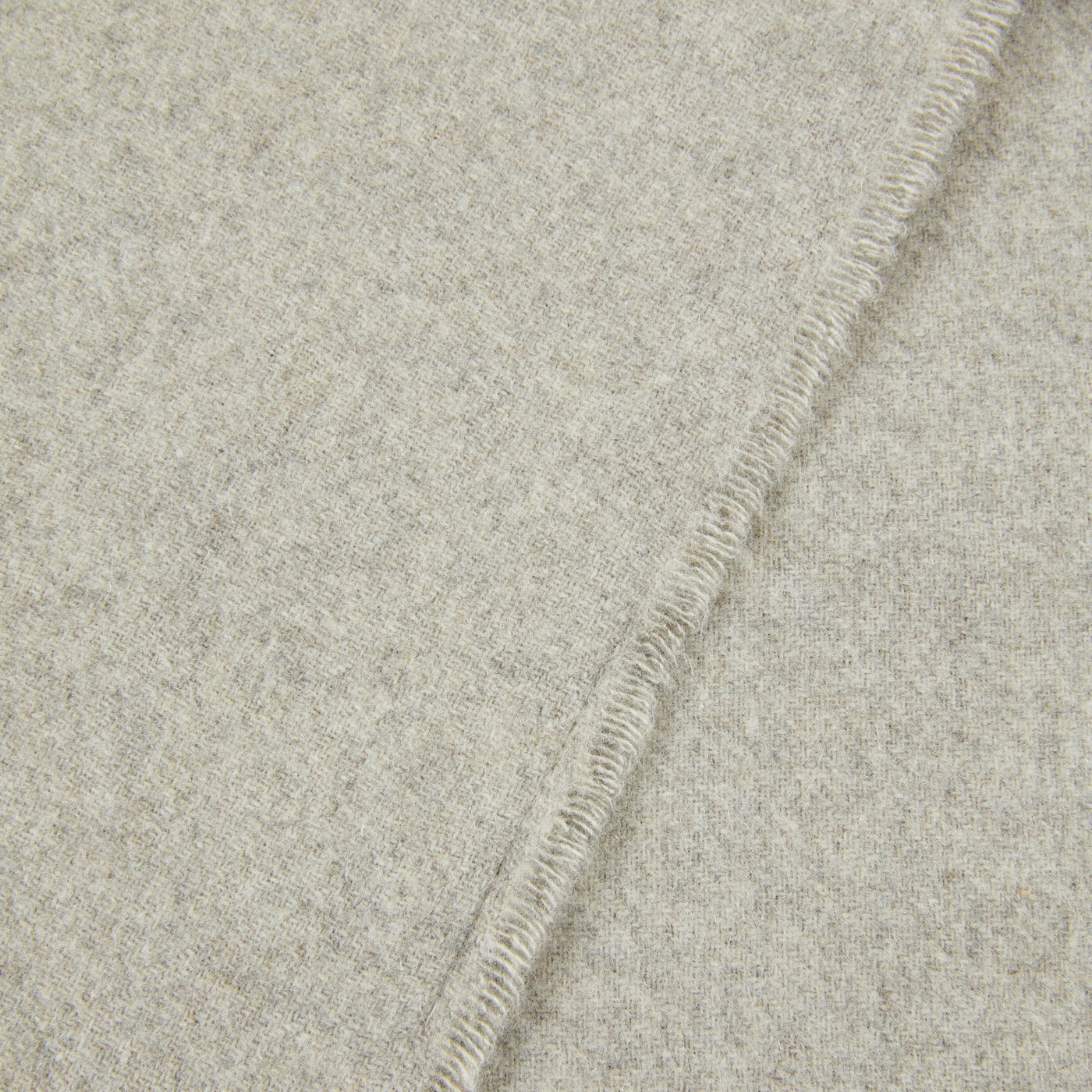 Close-up of Lanerossi Everest Check throw's whipstitch edge in oatmeal wool.