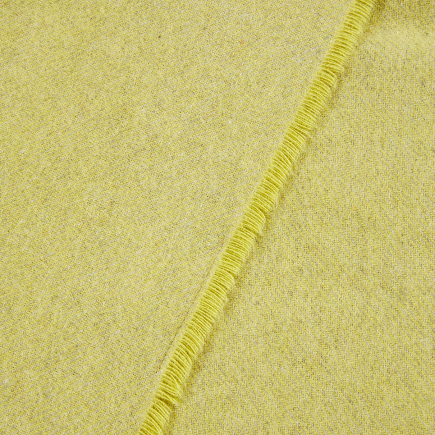 Close-up of citron wool throw corner with matching fringed edge detail.