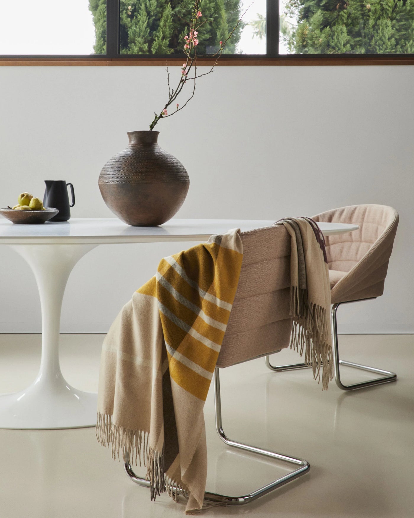 Ochre and sand fringed throw draped over a modern chair, bold check pattern visible.