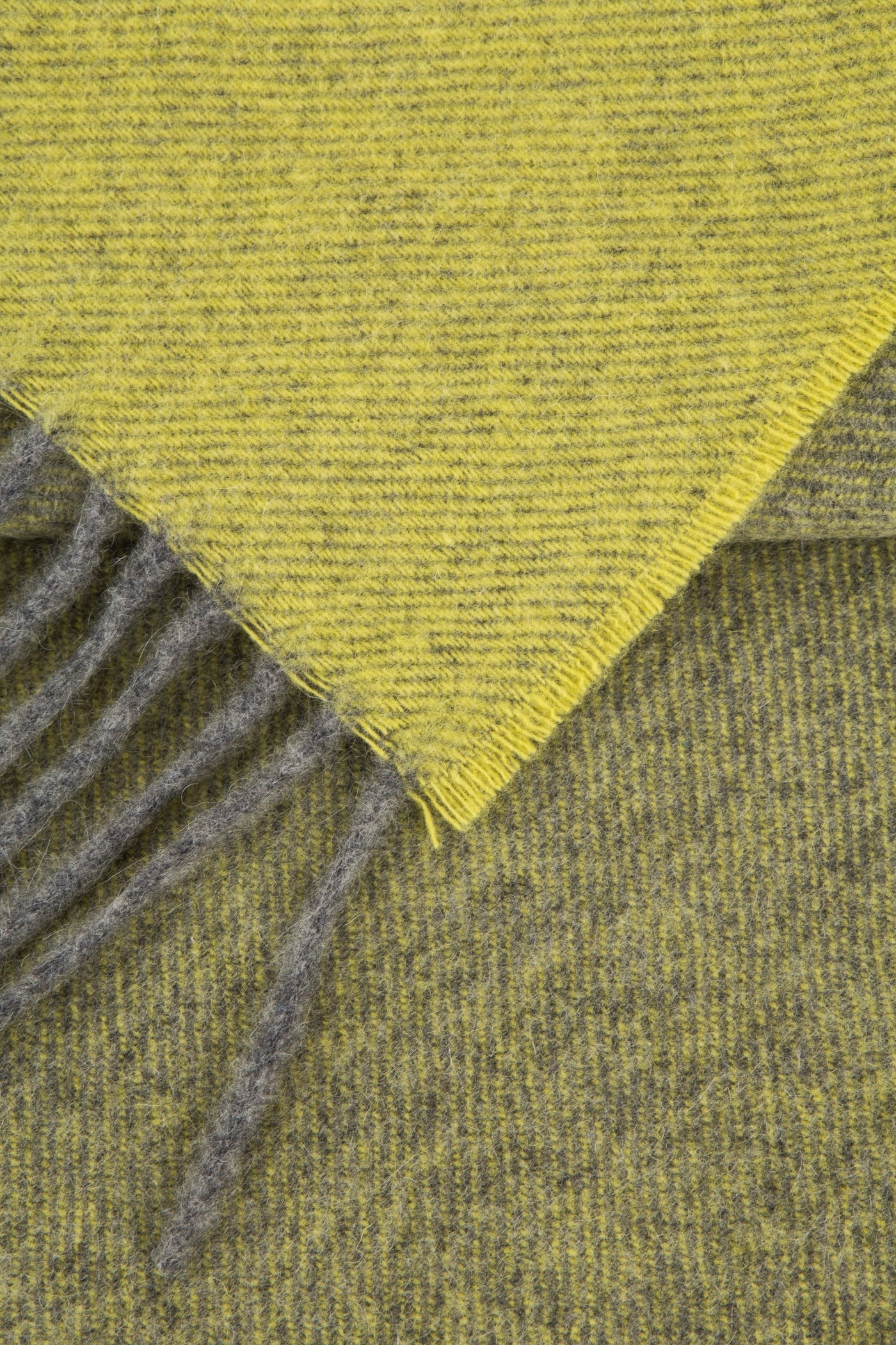 Corner detail of Lanerossi Everest Colour throw, chartreuse and grey reversible wool with fringe.