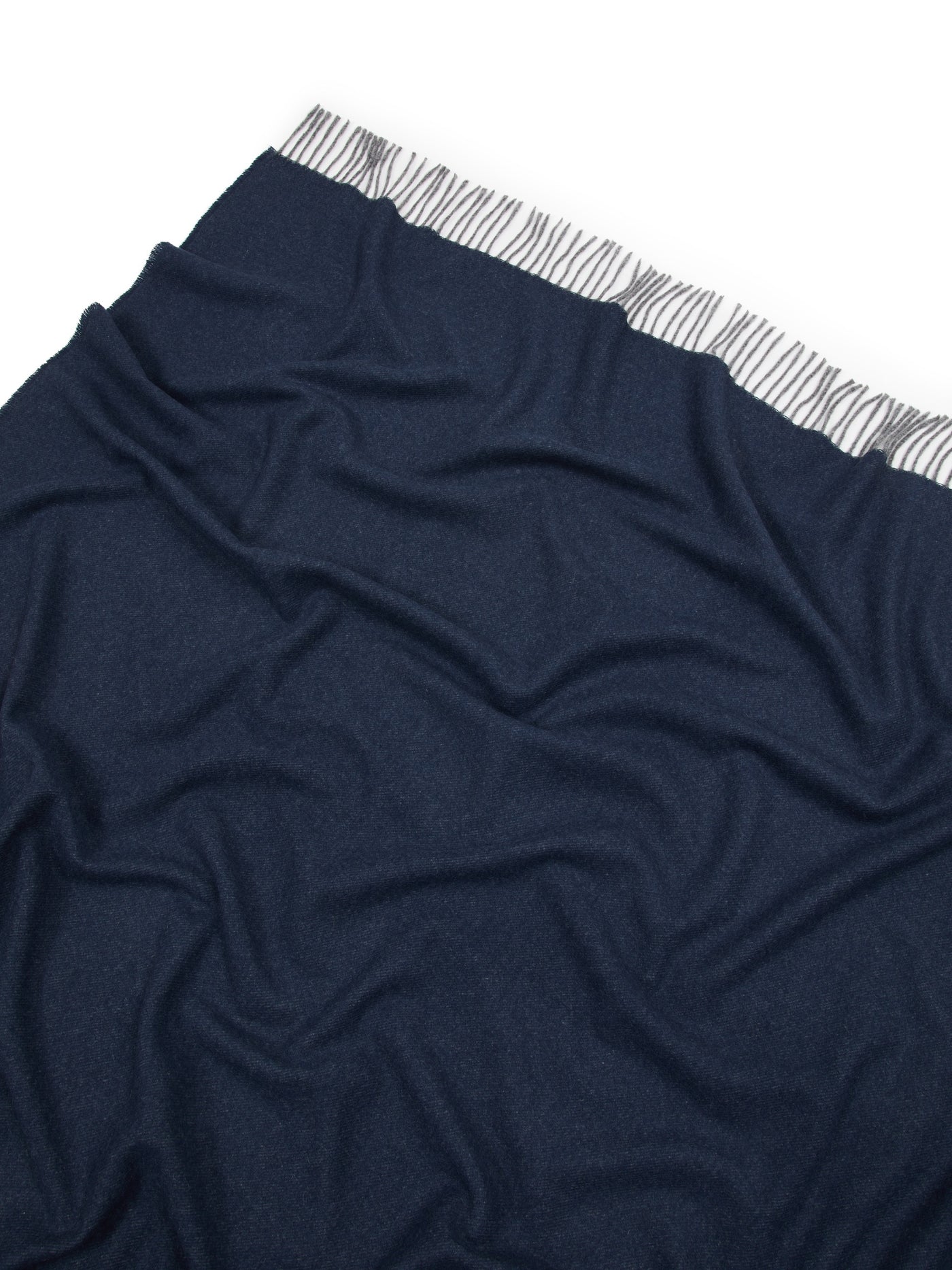 Navy throw draped loosely, showing striped woven trim detail along the top edge.