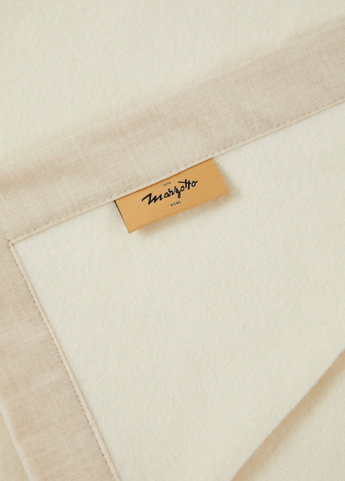 Close-up of Lanerossi Geisha blanket corner showing ivory wool face and sand border with woven label.