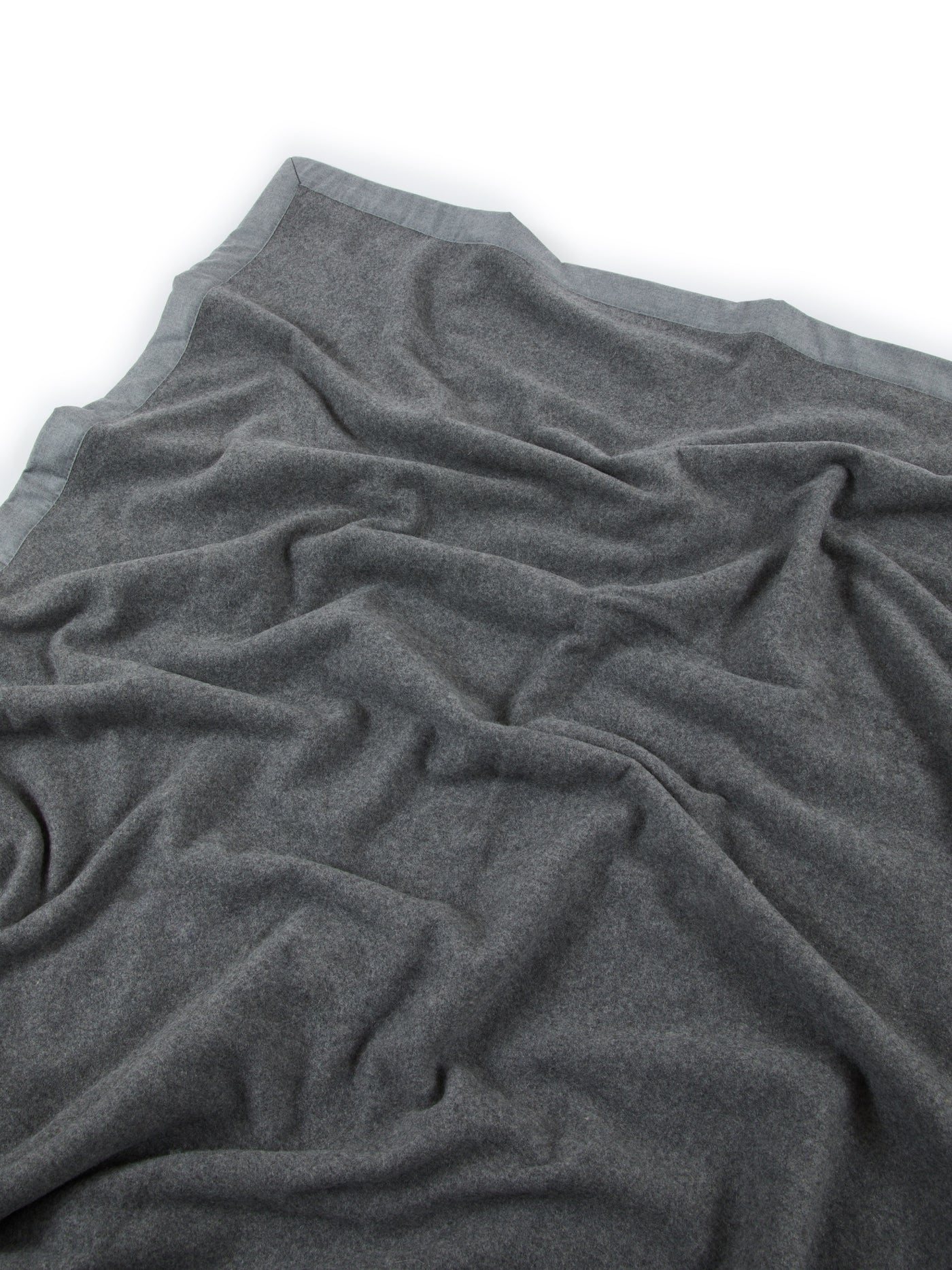 Close-up of Lanerossi Geisha blanket in charcoal, showing soft draped wool texture and satin trim edge.