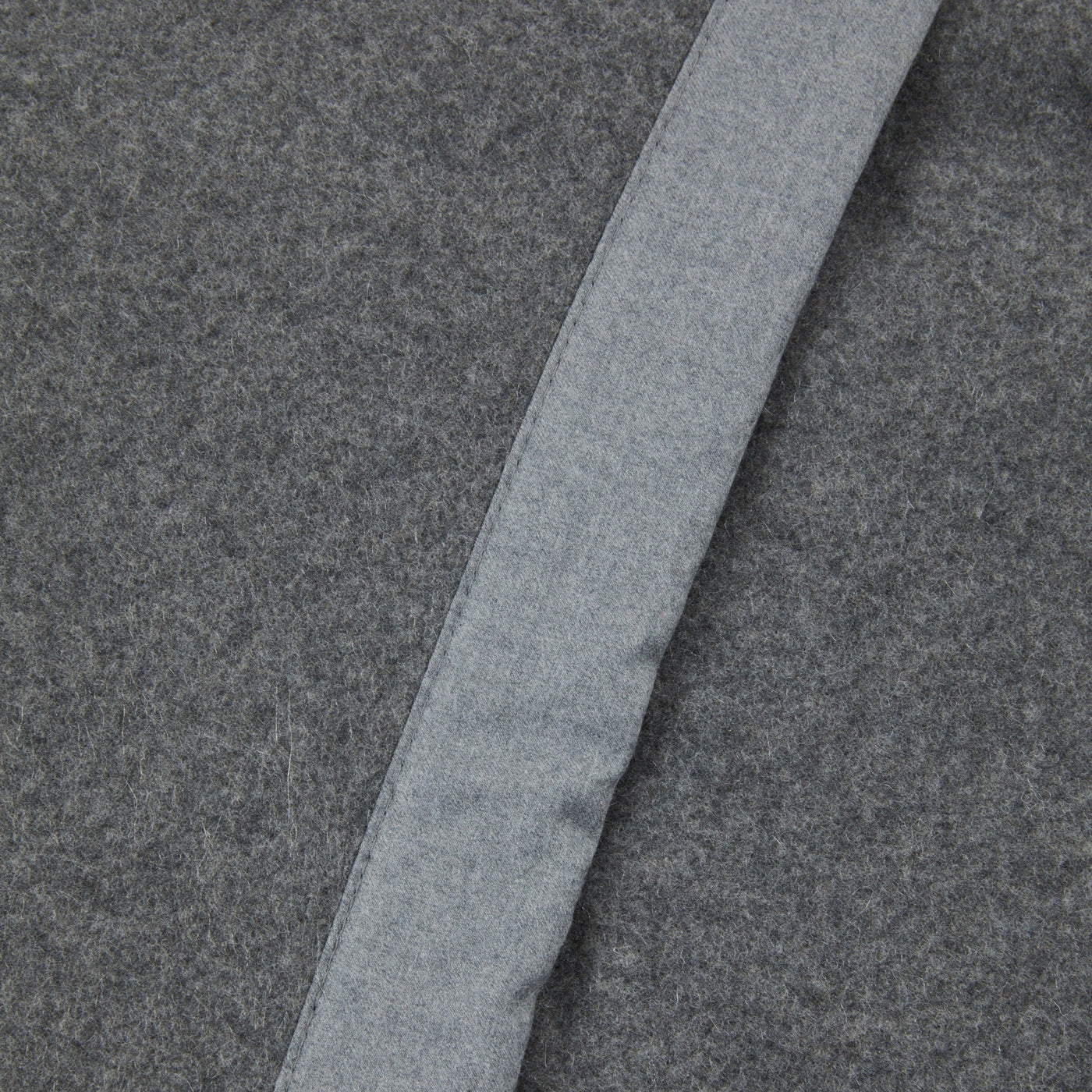 Close-up of Lanerossi Geisha blanket hem, showing light grey satin binding against charcoal wool.