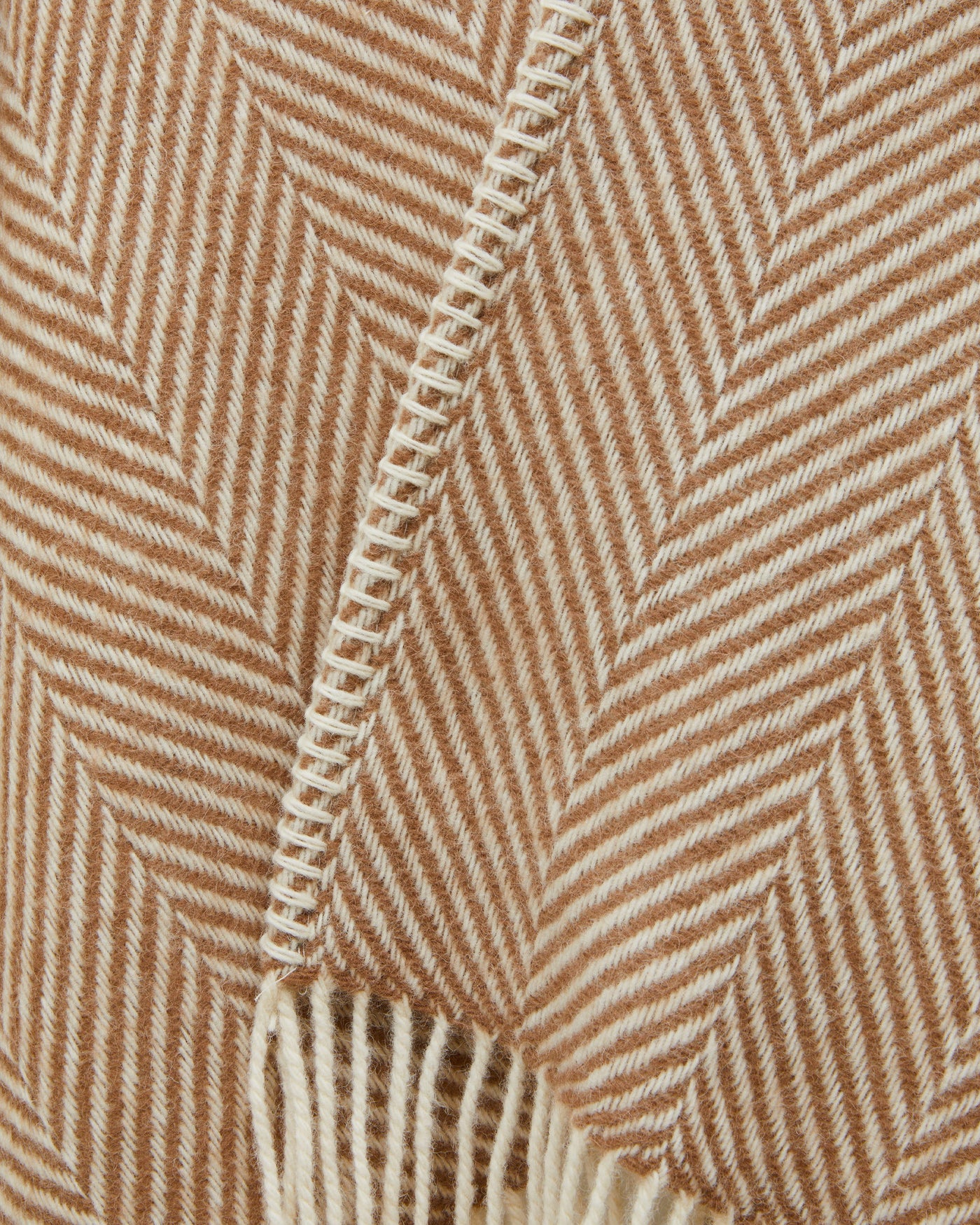 Close-up of camel herringbone weave with blanket-stitch edge and fringe detail.