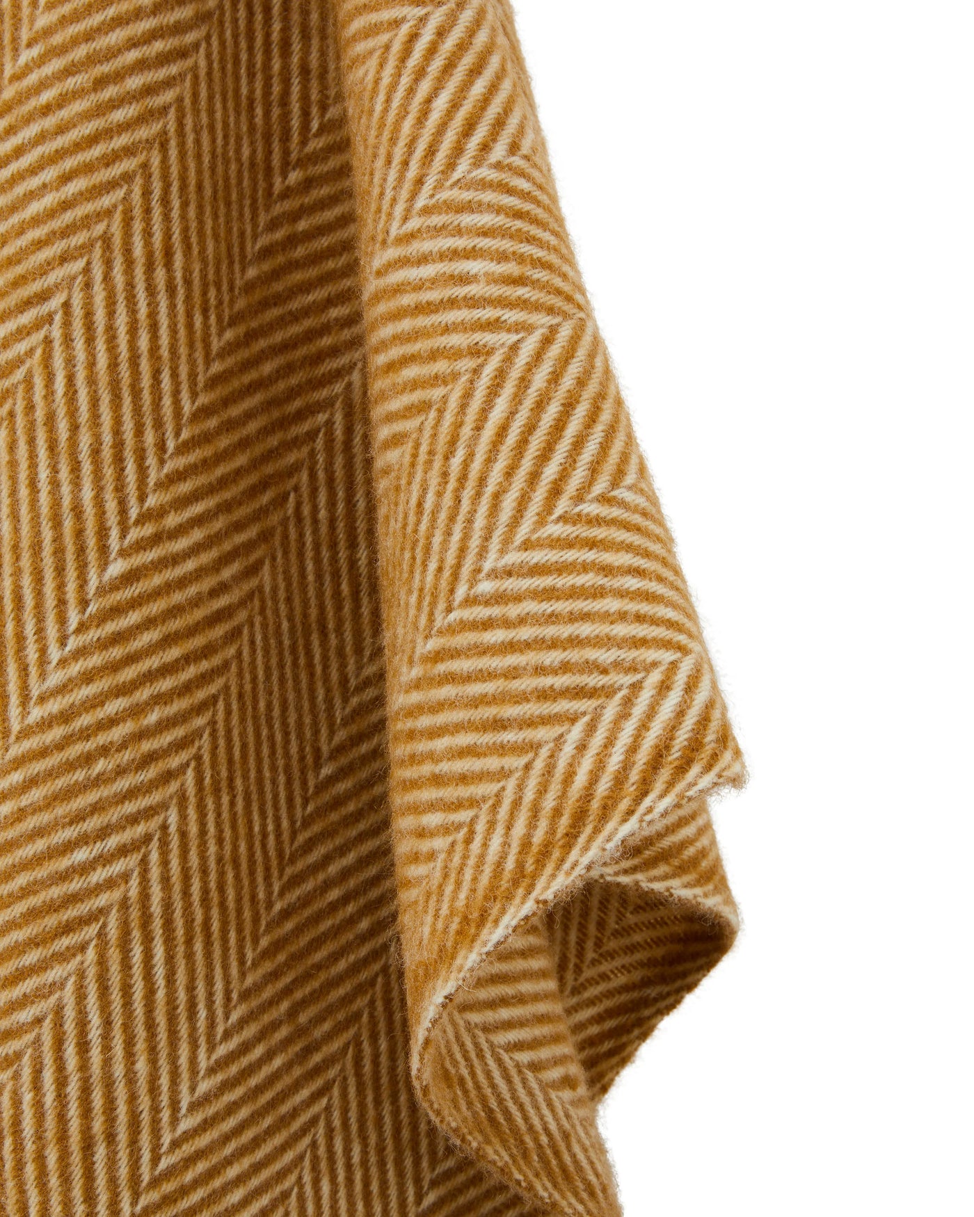 Close-up of saffron and ivory herringbone weave texture on draped wool poncho.