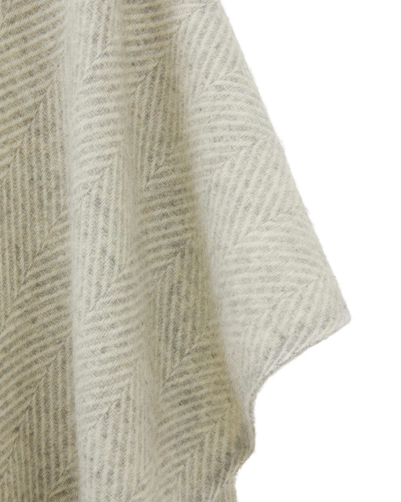 Close-up of ivory and grey herringbone weave on draped wool poncho fabric.