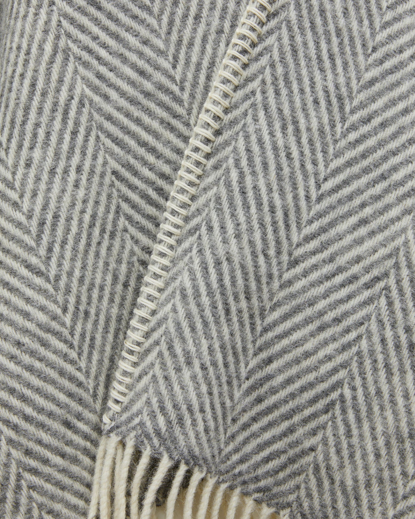 Close-up of Lanerossi Iseo Spina poncho in grey herringbone weave with ivory fringe detail.