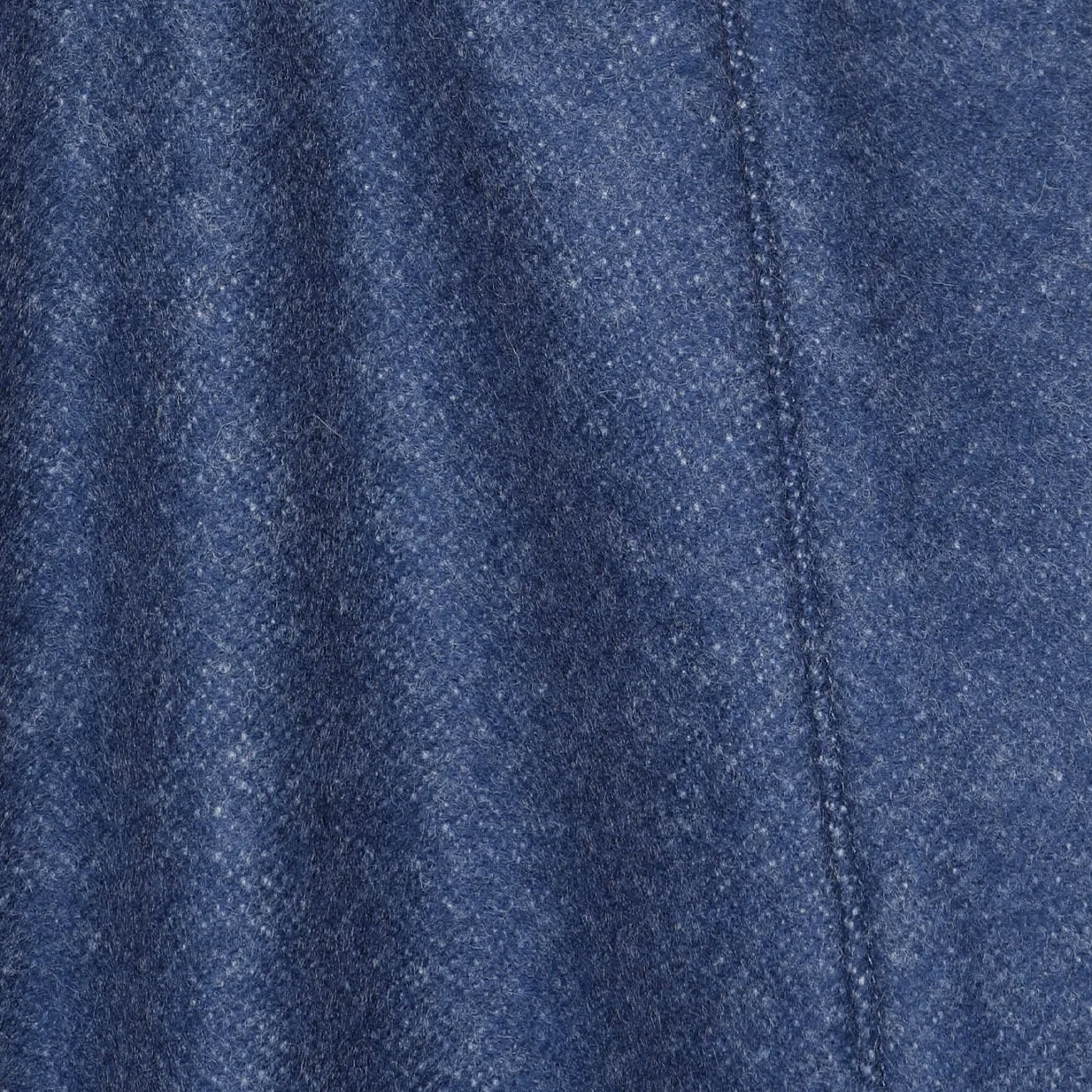 Close-up of indigo blue merino wool weave texture with visible seam detail.