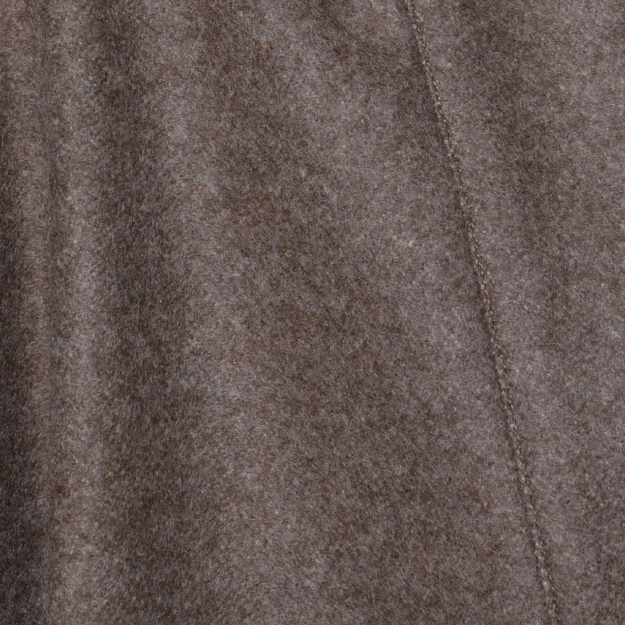Close-up of draped taupe merino wool fabric showing fine seam detail.