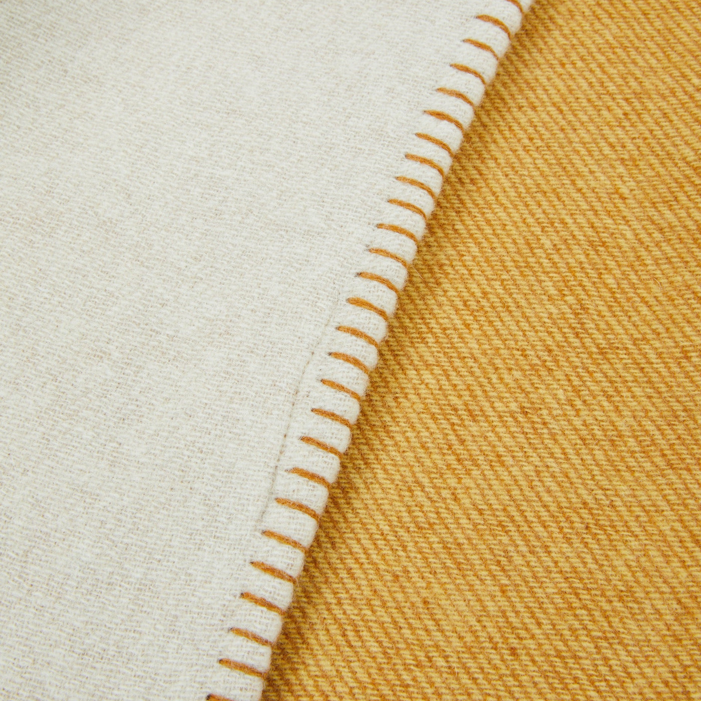 Close-up of Lanerossi Metropolis throw hem, ivory and saffron reversible wool with blanket-stitch edge.