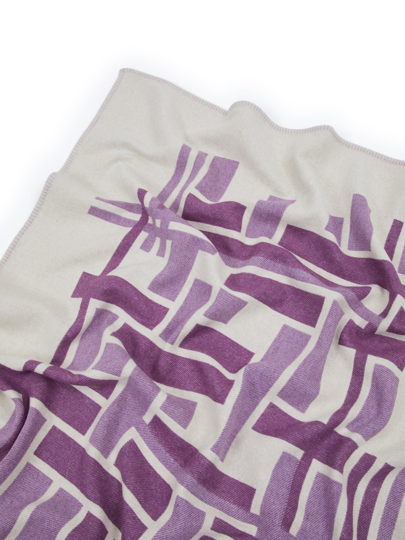 Close-up of Lanerossi Metropolis throw showing purple geometric pattern on ivory ground.