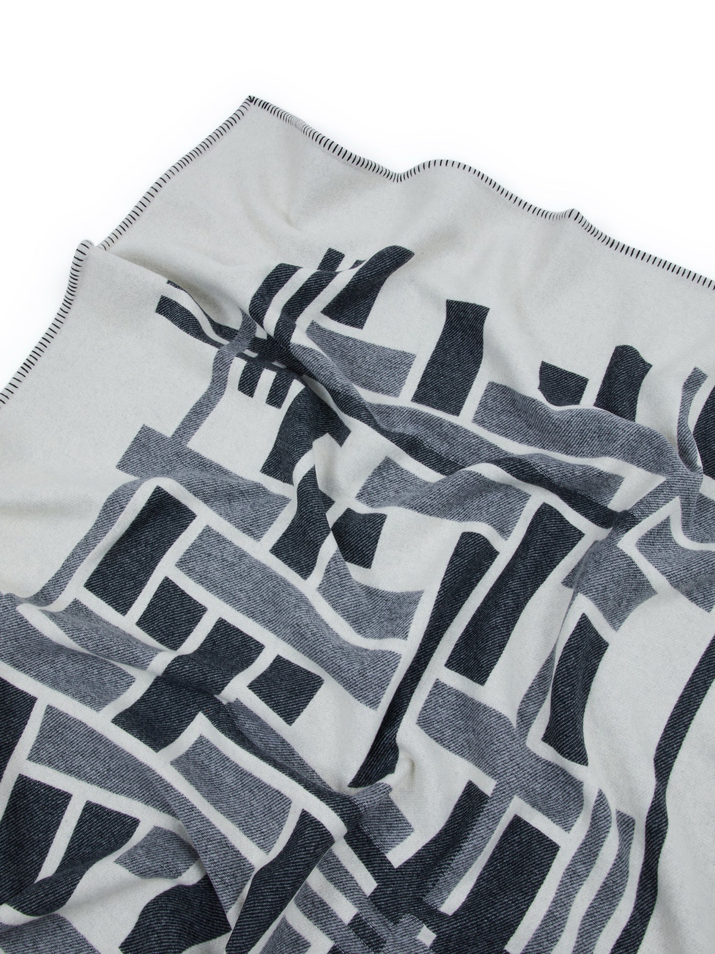 Close-up of Lanerossi Metropolis throw, ivory with navy geometric pattern and contrast stitched edge.